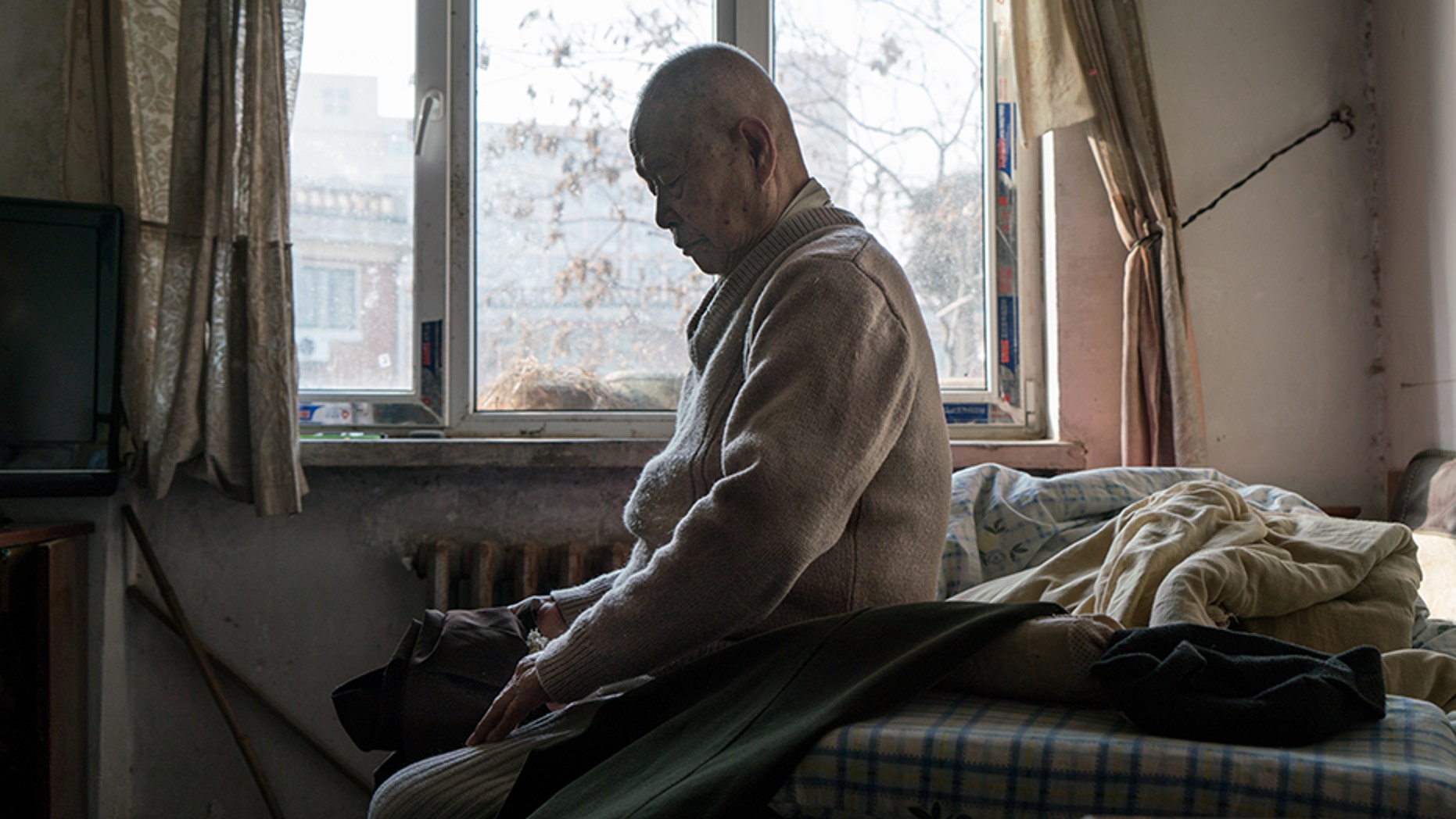 TIANJIN, CHINA - JANUARY 19: Han Zicheng, 85, sits in bed to take off his pants, revealing the wool pants inside that he usually wears at home. (Photo by Yan Cong for The Washington Post via Getty Images)