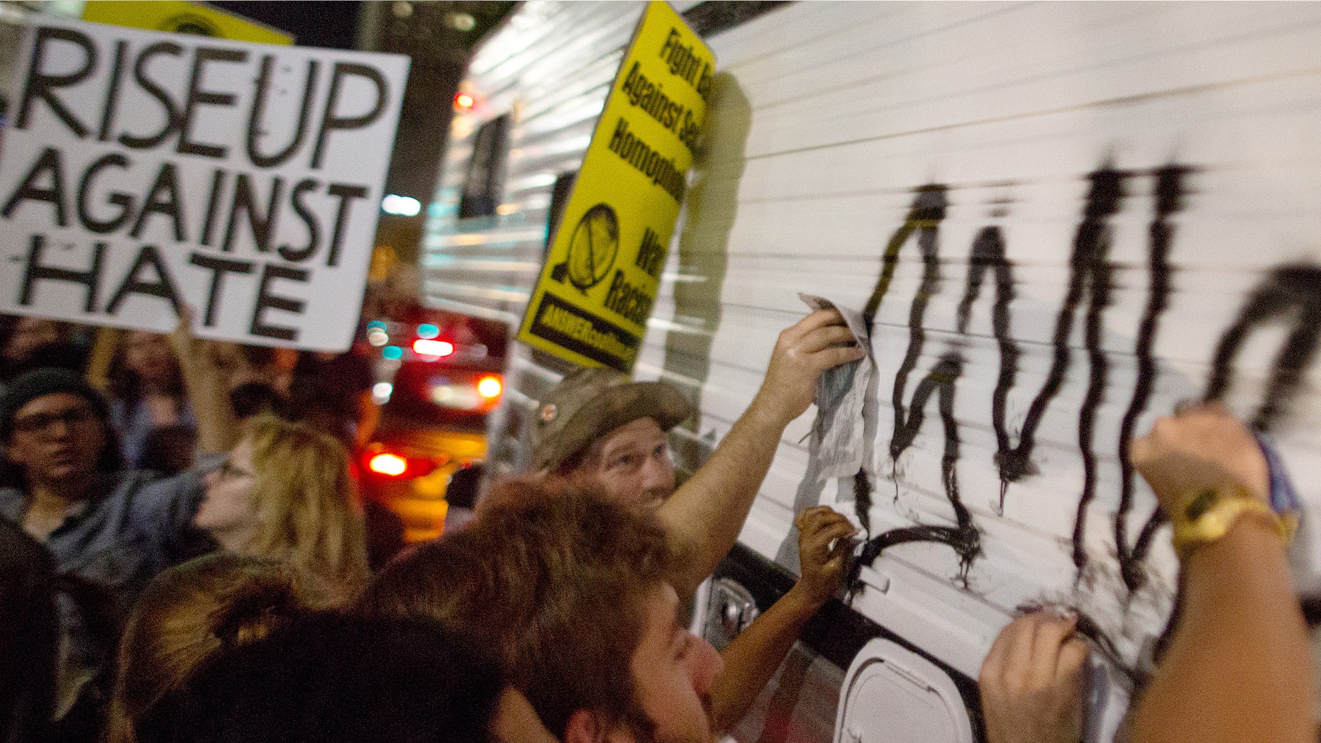 Protesters clean graffiti from a vandalized vehicle on November 9 2016 in Los Angeles, California, United States.