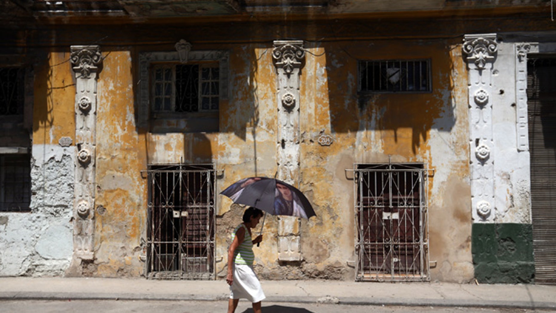 HAVANA, CUBA - SEPTEMBER 18: A woman shelters from the heat under an umbrella as she walks along a street on September 18, 2015 in Havana, Cuba. Pope Francis is due to make a three day visit to Cuba from September 19 where he will meet President Raul Castro and hold Mass in Revolution Square before travelling to Holguin, Santiago de Cuba, El Cobre and onwards to the United States. (Photo by Carl Court/Getty Images)