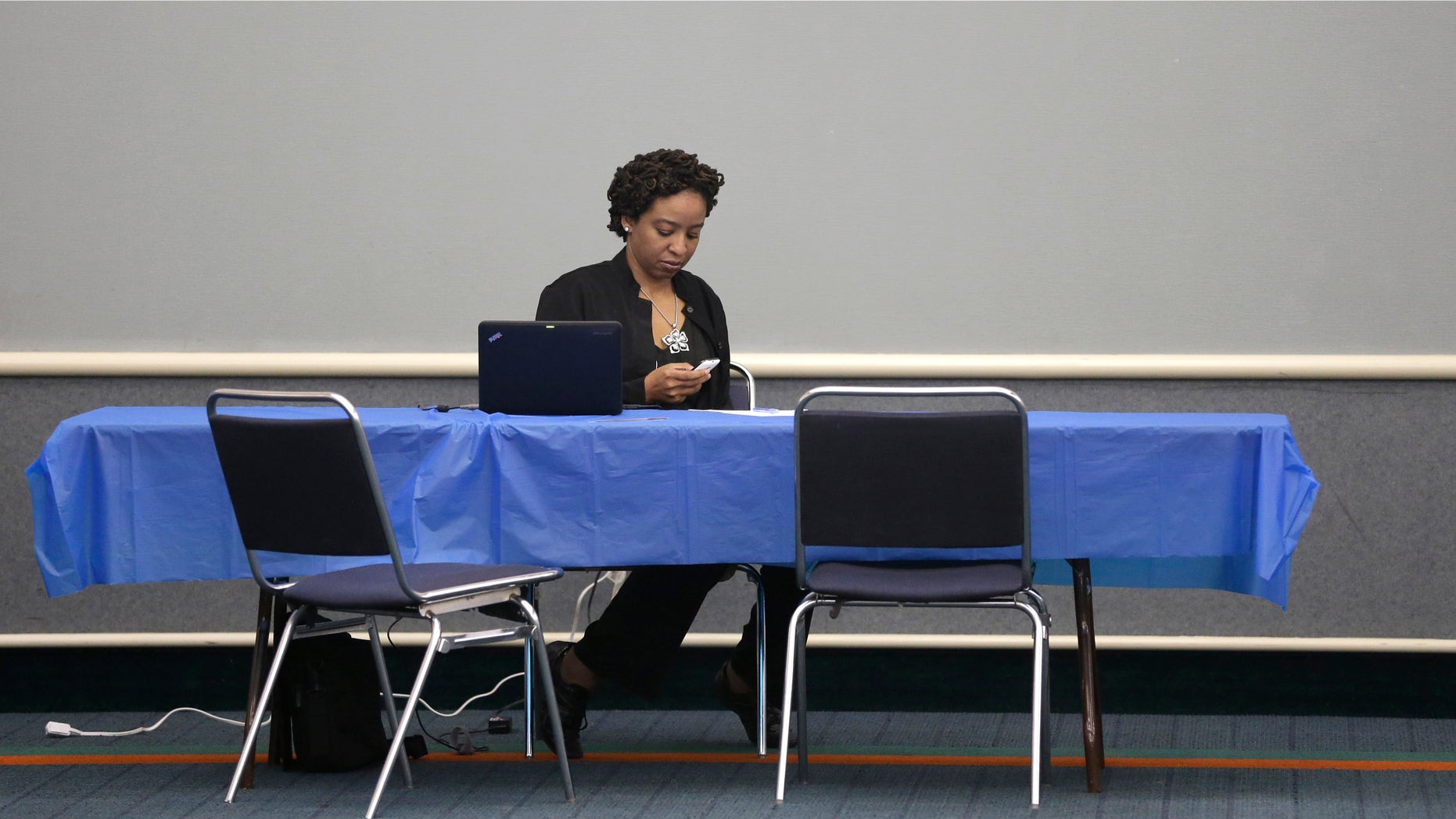 Health care assister Charolyn Mosley looks at her cell phone as she waits to help anyone looking to shop the federal marketplace for health insurance at a convention center in Texas City, Texas, Saturday, March 1, 2014. Though organizers had recruited assisters to handle as many as 400 people in navigating the federal insurance marketplace, only a handful had come by in the first hours of operations.
