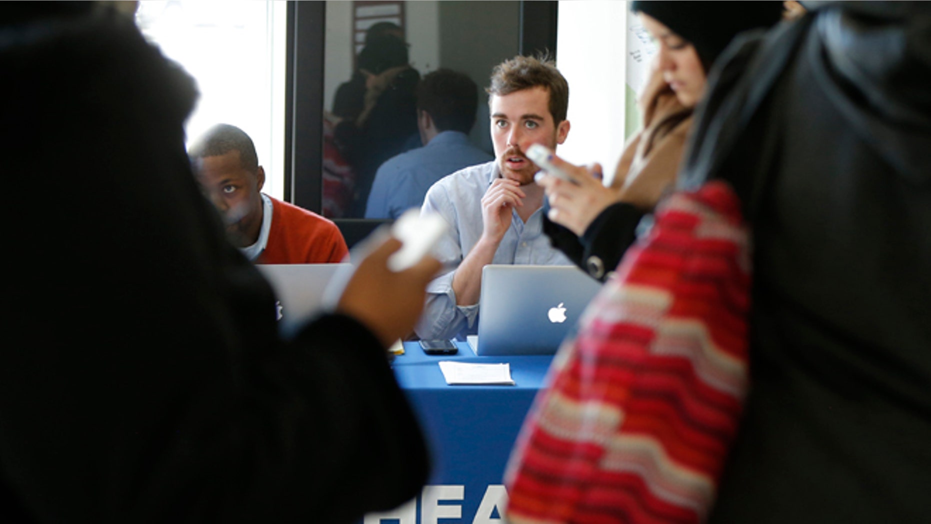 David Bransfield, a state outreach coordinator for Young Invincibles, a group which supports President Barack Obama's health care law, right, is seated with Dr. Christopher Riley, left, of Assist DC, as they look to sign up students for health care at the University of the District of Columbia in Washington, Thursday, Jan. 30, 2014. An army of workers and volunteers has fanned out around the country trying to enroll young and healthy people in health insurance now available through Obamaâs signature law. (AP Photo/Charles Dharapak)