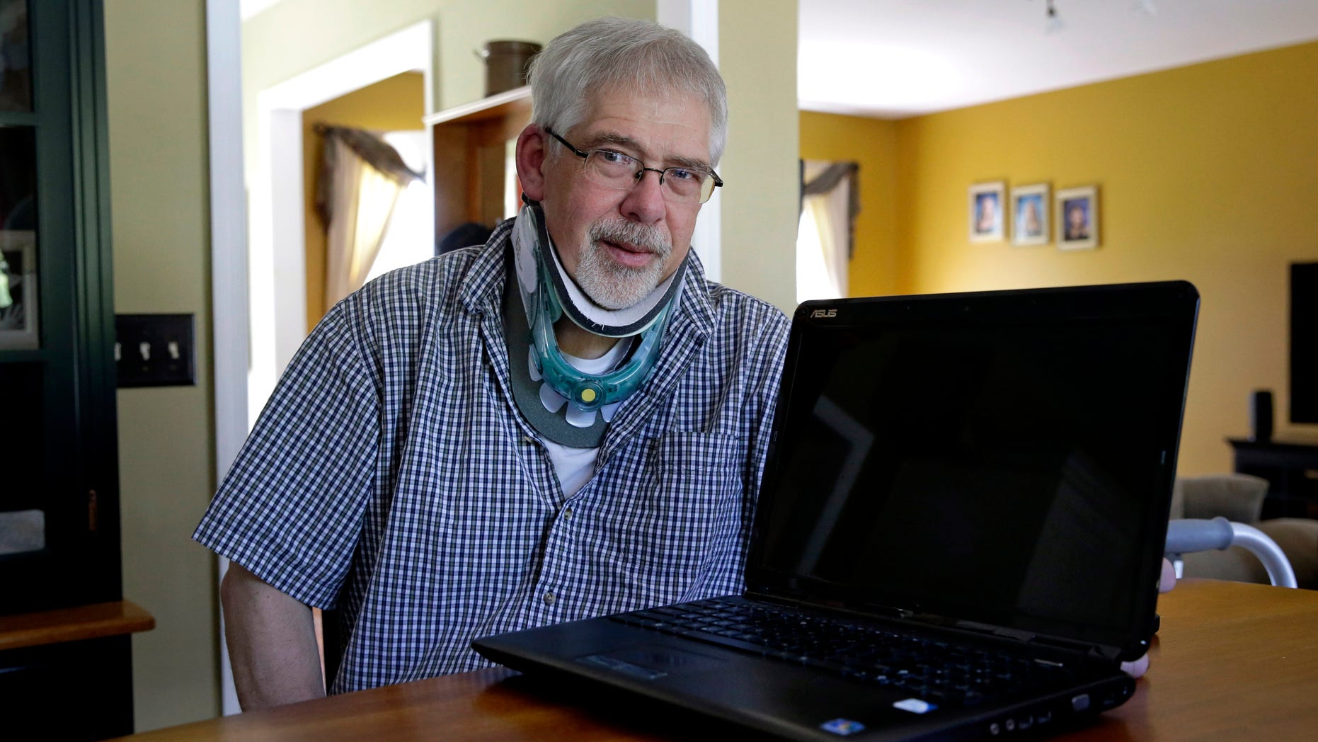 Mark Matulaitis poses with the laptop that he uses for virtual house calls with his neurologist in his home in Salisbury, Md. Matulaitis has had Parkinson's disease since 2011 and sees a neurologist at the University of Rochester via his laptop and special Skype-like software. (AP Photo/Patrick Semansky)