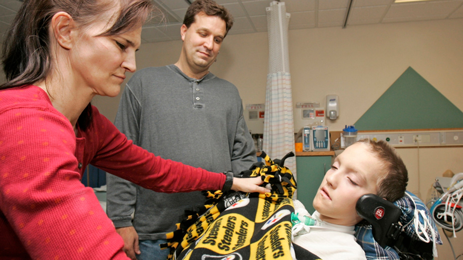 FILE - In this Jan. 9, 2009 file photo, Beth Malarkey, left, covers up her son, Alex, right, with a blanket after surgery as Alex's father, Kevin, watches at University Hospital's Case Western Reserve Medical Center in Cleveland. Alex Malarkey was in a 2004 car crash left him paralyzed below the neck and was receiving an artificial breathing device. Spokesman Todd Starowitz of Tyndale House, a leading Christian publisher, confirmed Friday, Jan. 16, 2015, that Alex Malarkeys The Boy Who Came Back from Heaven: A Remarkable Account of Miracles, Angels, and Life Beyond This World was being withdrawn. Earlier this week, Alex Malarkey acknowledged in an open letter that he was lying, saying that he had been seeking attention. The book was first published in 2010. (AP Photo/Tony Dejak, File)