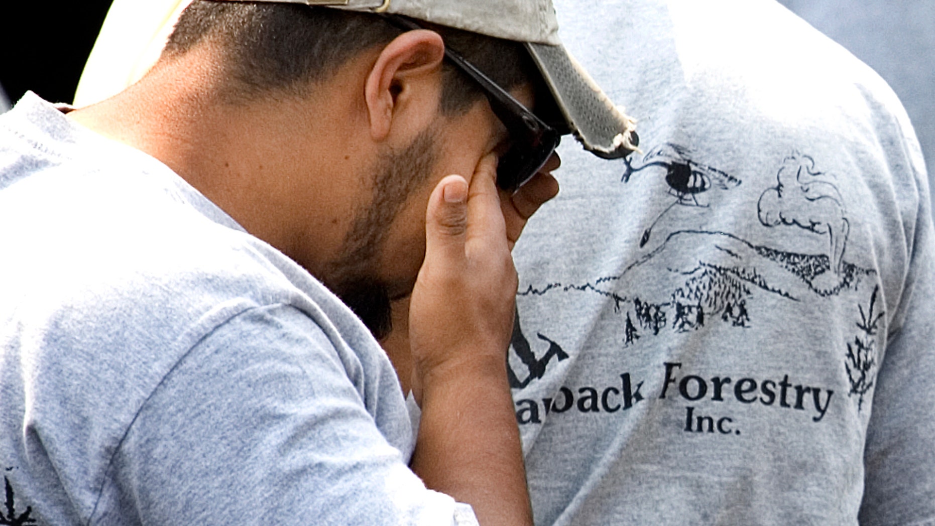 FILE - In this Aug. 8, 2008, file photo a firefighter from Grayback Forestry wipe away a tear at a company facility in White City, Ore., after hearing a helicopter crash killed seven fellow firefighters. A federal judge in Medford, Ore., on Monday, June 15, 2015, postponed sentencing a day for a former executive of Carson Helicopters who admitted to falsifying performance records for the helicopter that crashed to win a lucrative U.S. Forest Service contract. (AP Photo/Don Ryan, File)