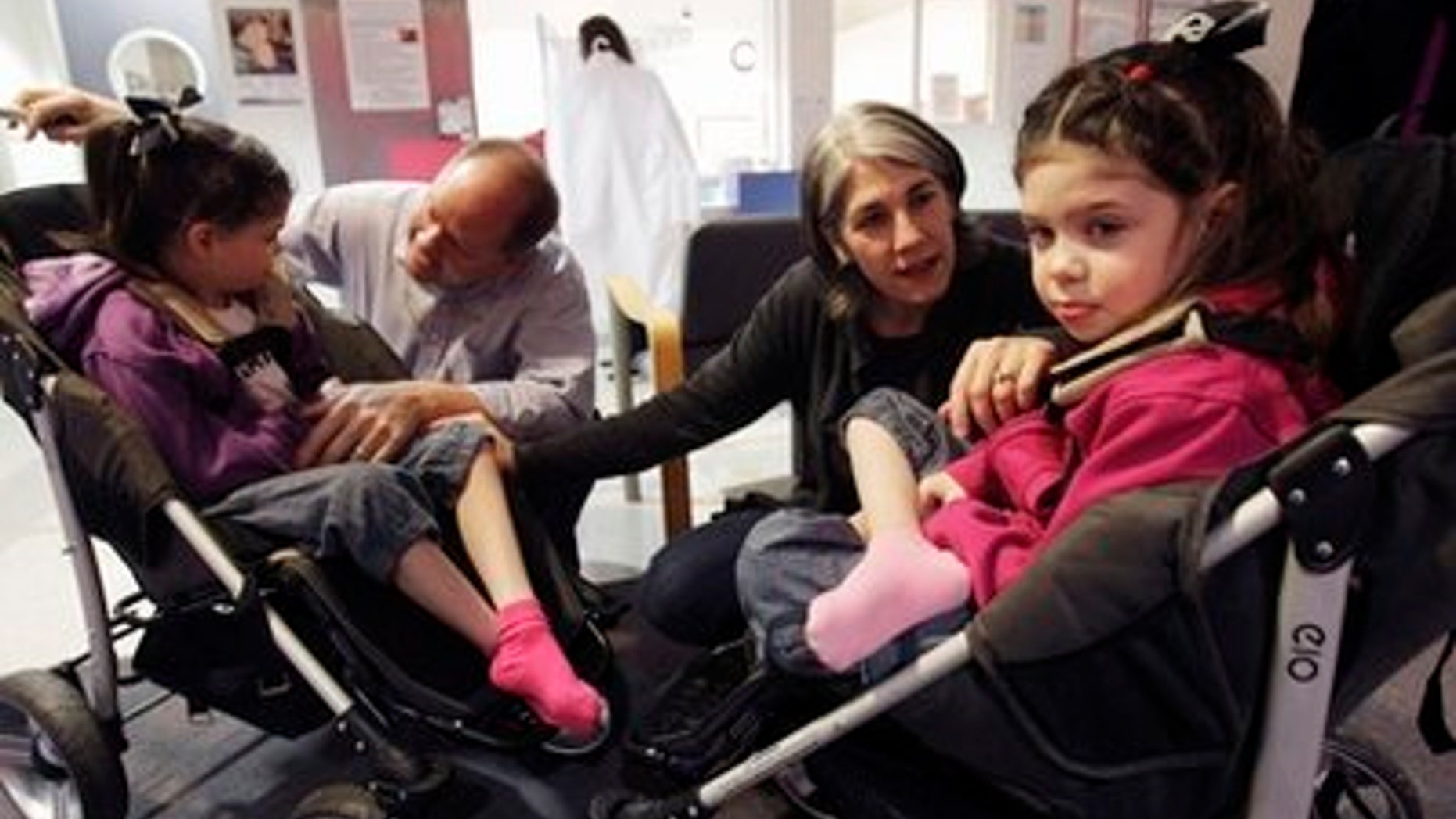 The Hempels, from left, Cassidy, 6, her father Hugh, mother Chris and twin sister Addison gather in the lobby at the Children's Hospital and Research Center in Oakland, Calif., Friday, March 18, 2011. The Hempel twins are receiving alternative treatment for Niemann Pick Type C disease, a rare disorder where harmful amounts of cholesterol accumulates in vital organs. Every other week, 7-year-old twins Addison and Cassidy Hempel have an experimental medicine injected into their spines in hopes of battling a fatal neurologic disease. It's not a drug company study — their mother won a government OK for the unusual exeriment. (AP Photo/Marcio Jose Sanchez)
