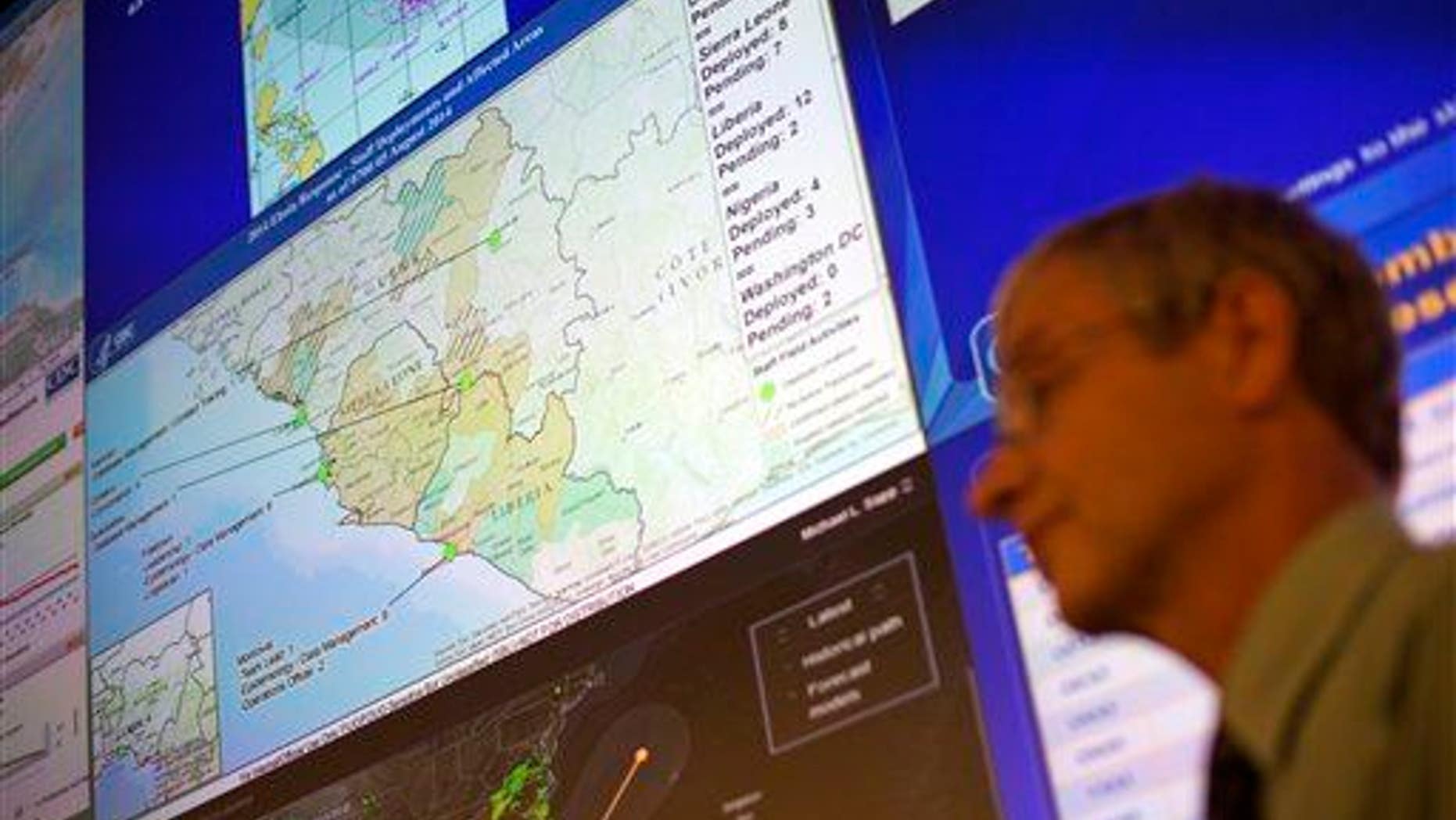 A CDC official stands under a map showing the agency's deployment of workers in West Africa at the agency's Emergency Operations Center, Tuesday, Aug. 5, 2014, in Atlanta.