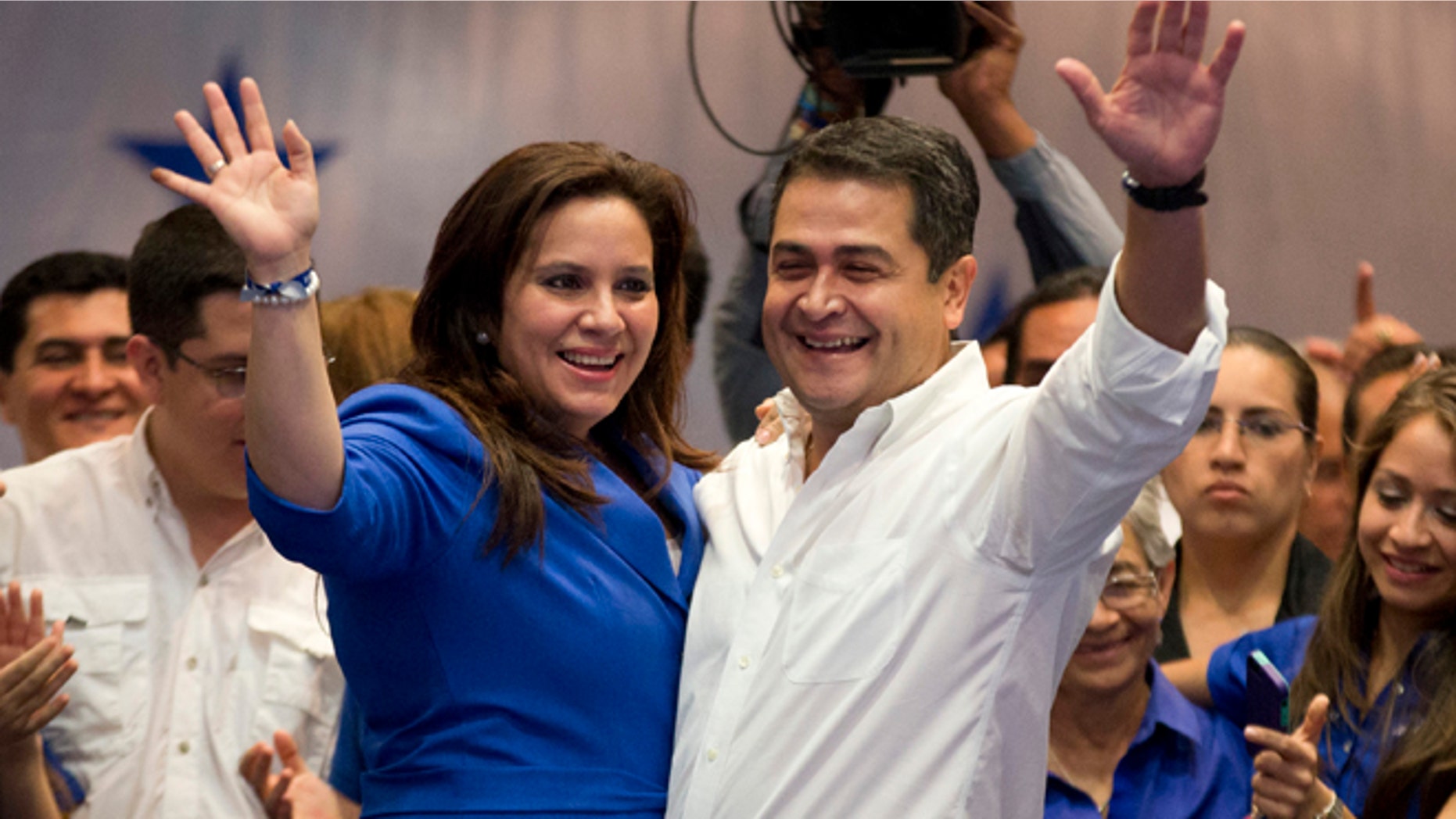 National Party presidential candidate Juan Orlando Hernandez and his wife, Ana Garcia, left, waves to supporters during his victory speech, after partial election results in Tegucigalpa, Honduras, Sunday, Nov. 24, 2013. The electoral court said preliminary results gave Hernandez a comfortable edge over Xiomara Castro, whose husband Manuel Zelaya was overthrown in the military-backed coup.(AP Photo/Eduardo Verdugo)