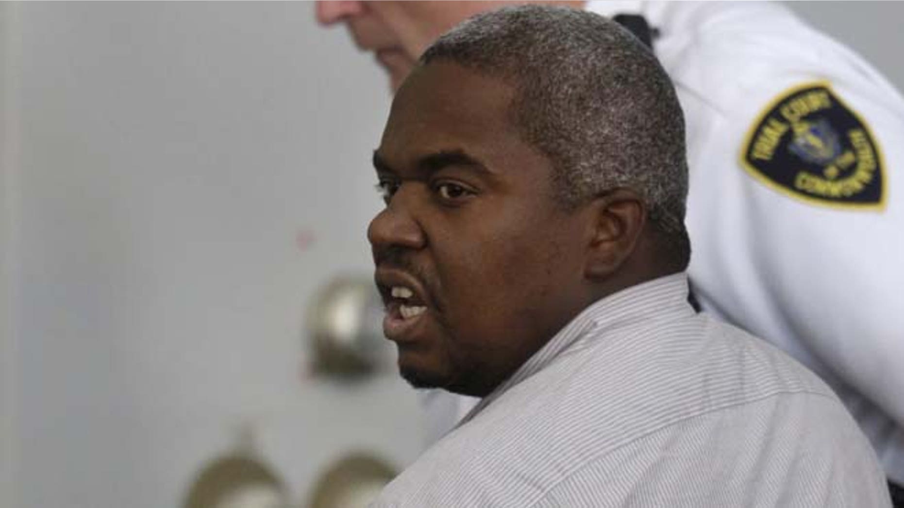 July 8, 2013: Ernest Wallace, of Miramar, Fla., mouths words to people sitting in Attleboro District Court, in Attleboro, Mass., as he is escorted from the court room after pleading not guilty during his arraignment. Wallace is facing an accessory to murder charge in the case involving former New England Patriots tight end Aaron Hernandez and has been ordered held without bail.