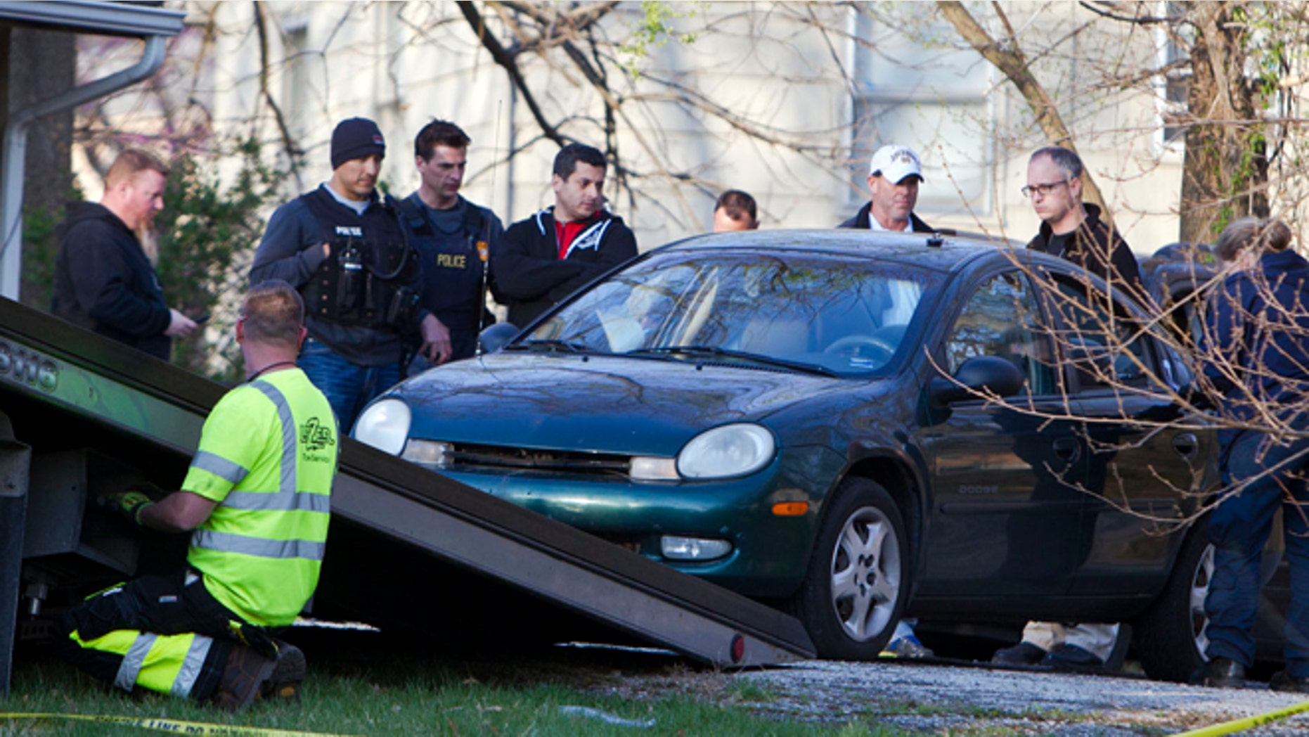 April 17: A car is removed by Kansas City police from the house, far right, of a Grandview man suspected in a series of shootings that have occurred on area roadways since early March, according to police.