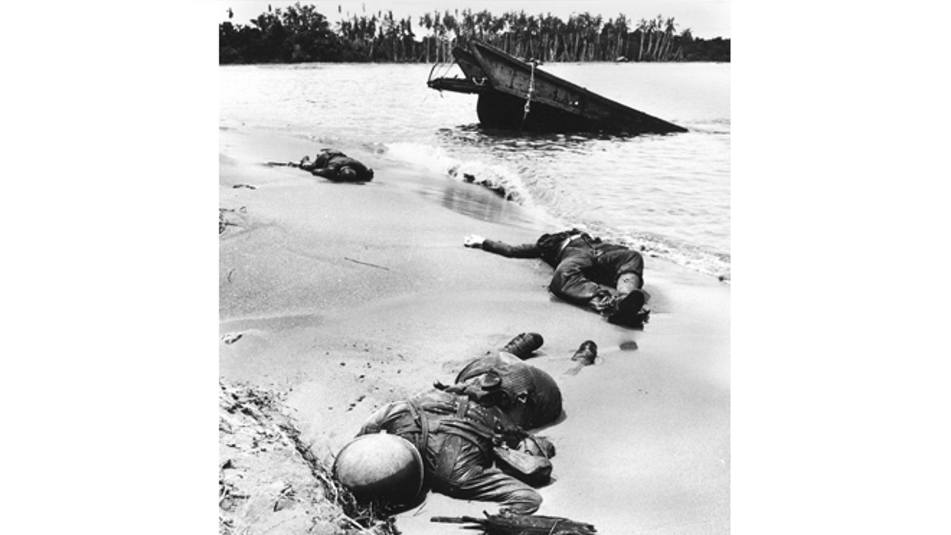 Three dead Americans lie on the beach at Buna.