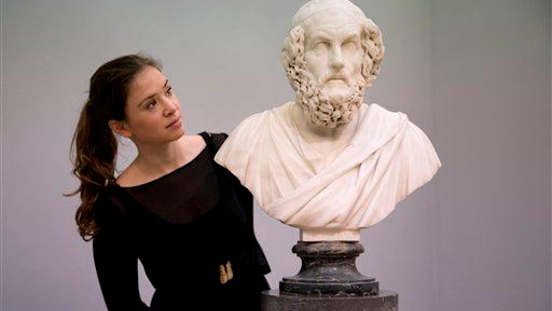 A Sotheby's auction house employee poses for photographs with the Francis Harwood marble bust of the ancient Greek poet Homer in London, Friday, Nov. 28, 2014.