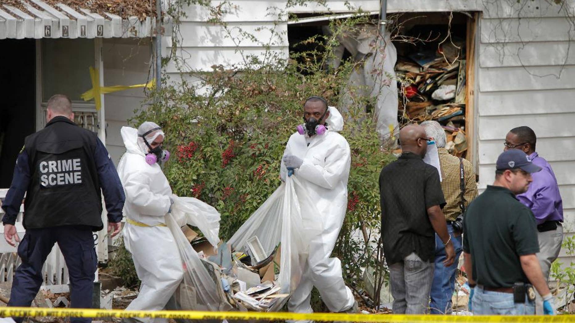Hazardous materials contractors for the city remove debris from the home where a body was found in the 6200 block of Martel Avenue in Dallas, Texas on Thursday, March 27, 2014. Dallas fire and police departments started searching the house following a welfare check on Saturday. Due to the circumstances the City Attorney’s office was contacted to obtain a warrant to provide a removal process of the debris from inside the home. A contractor was secured to begin the removal process. On Thursday the contractors reported that they had found a dead body inside the home. (AP Photo/The Dallas Morning News, Brad Loper)