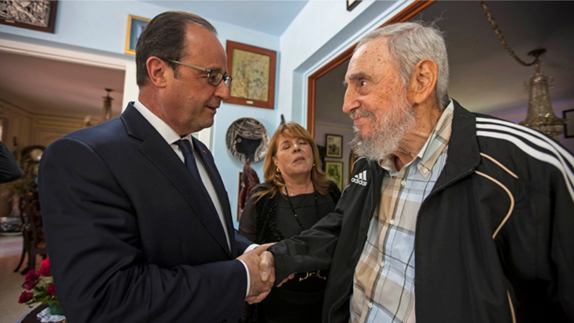 Cuba's former leader Fidel Castro, right, shakes hands with French President Francois Hollande in Havana, Cuba, Monday, May 11, 2015. The woman between the two men is a translator. Hollande is the first French leader to visit the island nation in more than a century and also the first Western leader to travel to Cuba since the surprise announcement in December of a rapprochement between Washington and Havana. (AP Photo/Alex Castro)