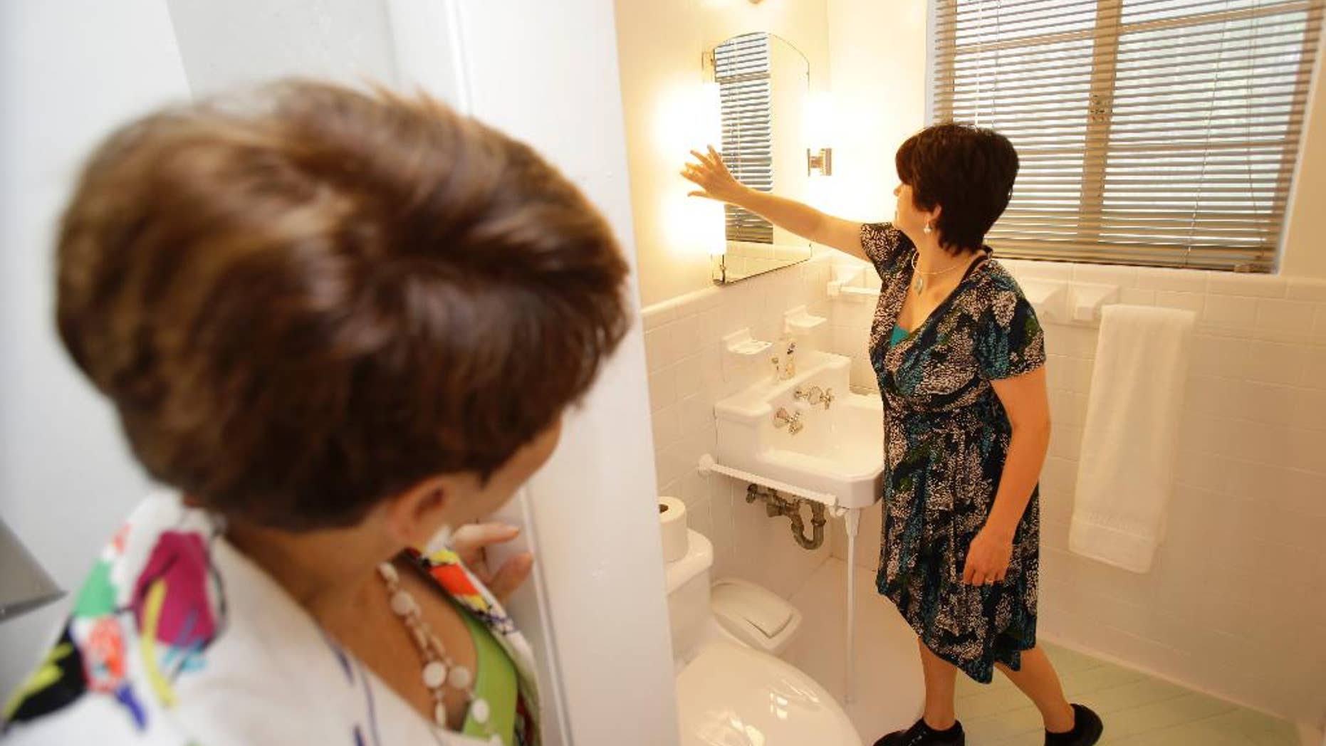 In this Thursday, May 29, 2014 photo, prospective buyer Mary Tuttle, right, checks out antique lighting fixtures while looking at a home with real estate broker Nancy Dowson, left, with Keller Williams Realty, in Miami Shores, Fla. The National Association of Realtors reports, on Monday, Sept. 22, 2014, on sales of existing homes in August. (AP Photo/Wilfredo Lee)