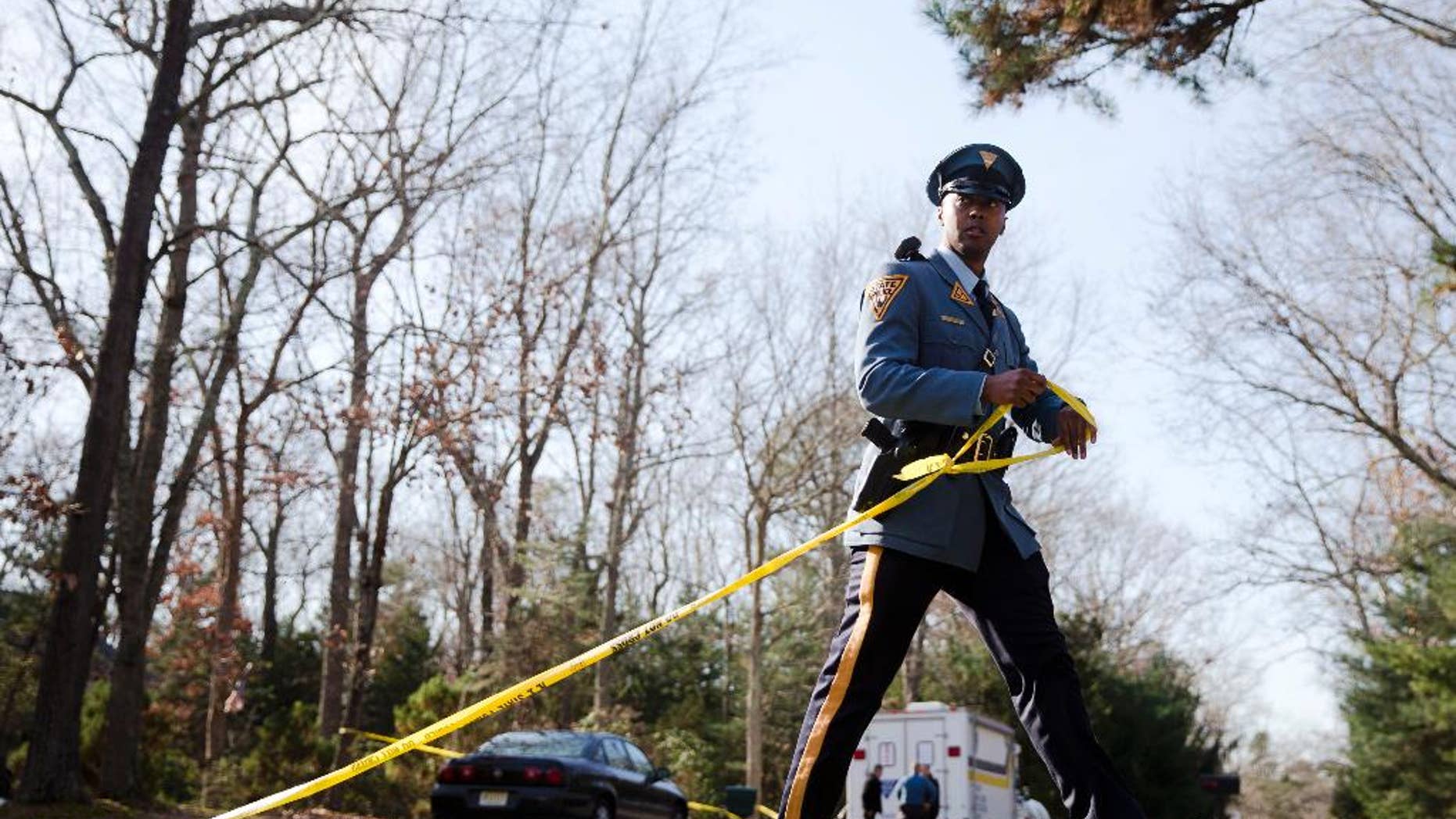 A New Jersey State Police trooper secures a police line at the scene of a shooting, Thursday, Nov. 20, 2014, in Tabernacle, N.J. A shooting at the home in a secluded wooded area of southern New Jersey left two children dead and a woman and another child wounded, state police said Thursday. (AP Photo/Matt Rourke)