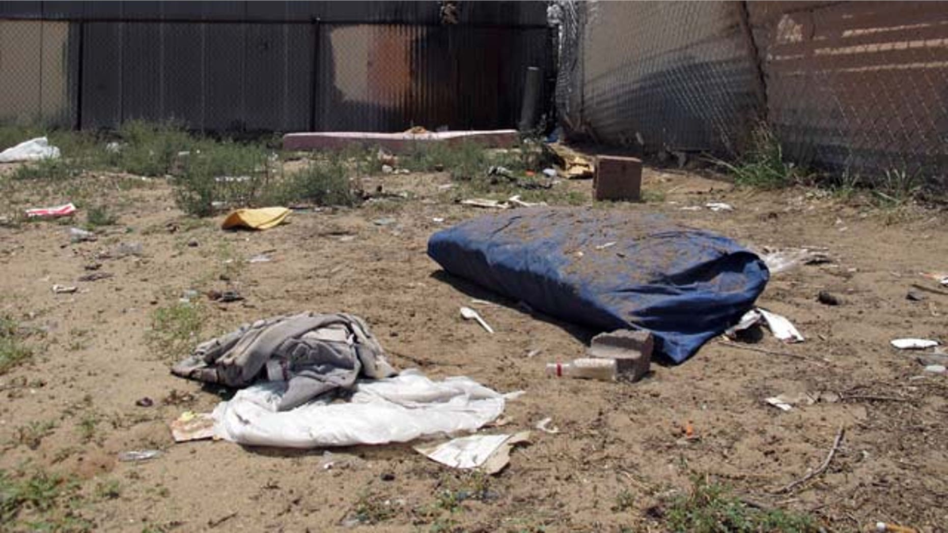 July 21, 2014: Bedding, clothing and broken glass litter a homeless encampment in Albuquerque where three teenagers are accused of fatally beating two homeless men. The teens, aged 15, 16 and 18, have been charged with open counts of murder in the Friday night killings. (AP Photo/Jeri Clausing)