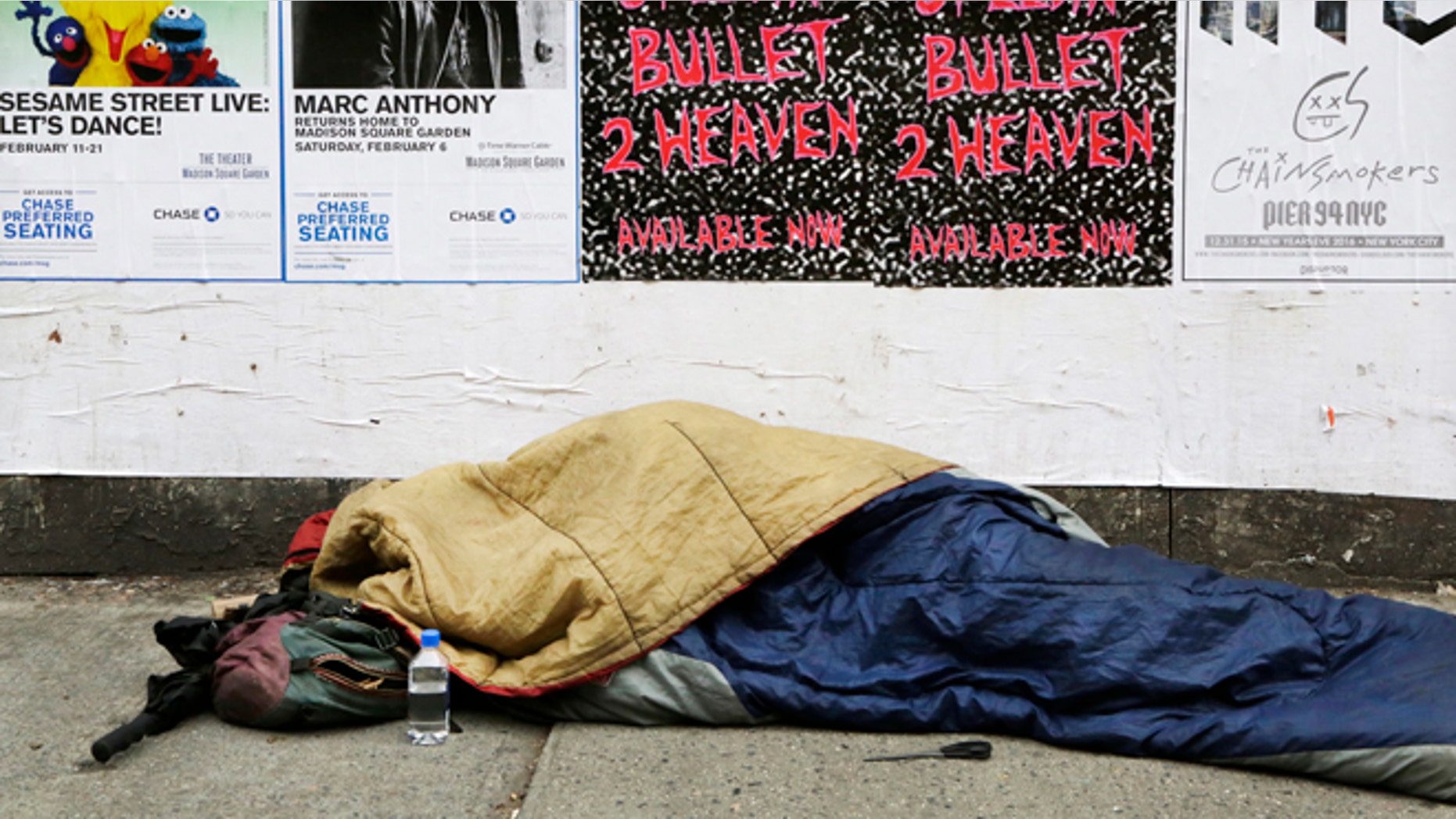 A homeless person sleeps on a sidewalk, Monday, Dec. 21, 2015 in New York. Homeless advocacy groups are threatening legal action against the city over its plans to conduct an aggressive homeless outreach program. The groups say they fear police involvement in the campaign will result in more arrests of homeless people. (AP Photo/Mark Lennihan)