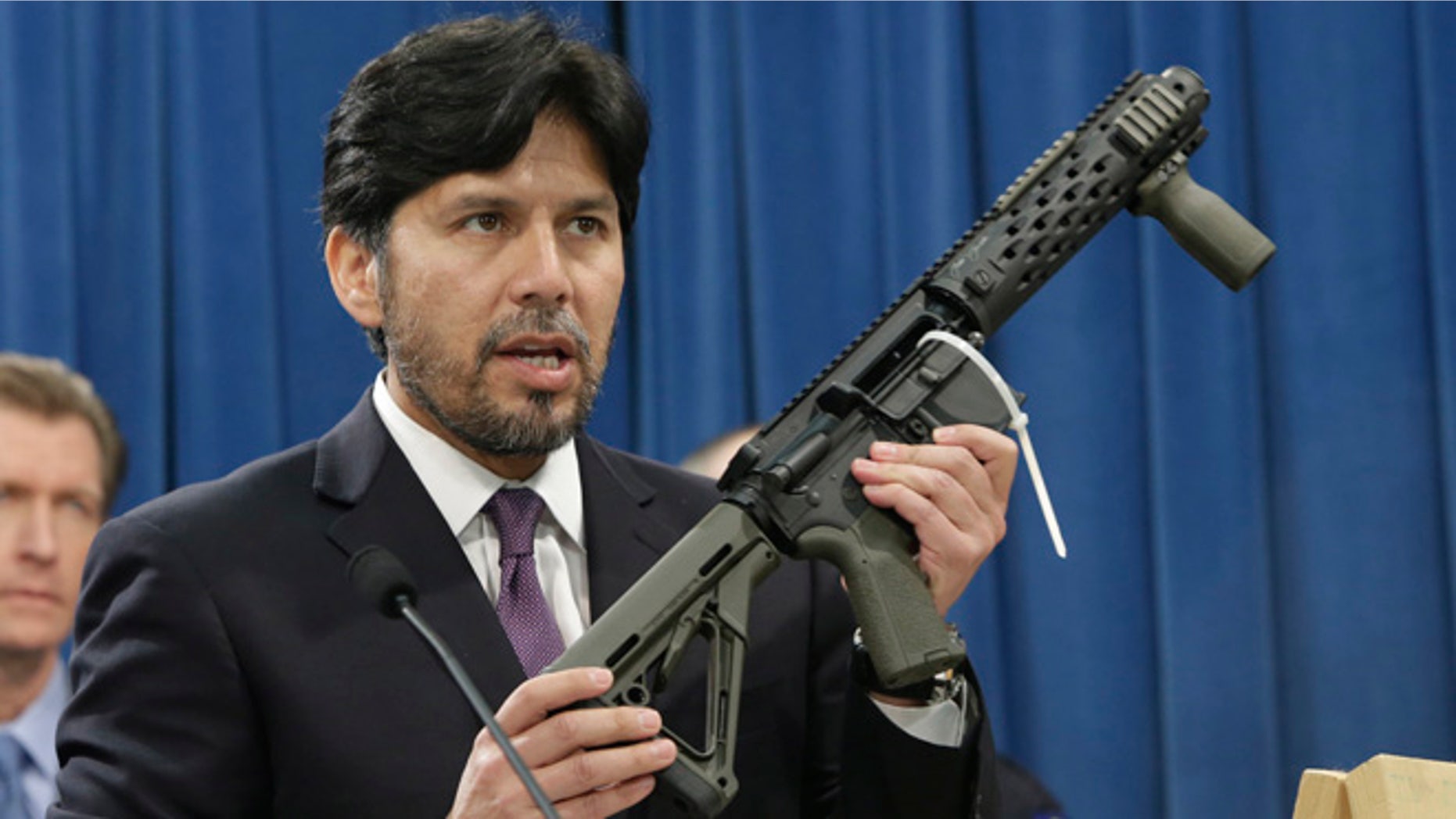 State Sen. Kevin de Leon, D-Los Angeles, displays a homemade fully automatic rifle, confiscated by the Department of Justice, as he discuss his proposed legislation dealing with "ghost guns," at the Capitol in Sacramento, Calif., Monday, Jan. 13, 2014. Under de Leon's measure, SB808 would allow the manufacture or assembly of homemade weapons, known as "ghost guns,", but require the makers to first apply to the state Department of Justice for a serial number that would be given only after the applicants undergo a background check. De Leon plans to amend the bill to also require that guns contain permanent pieces of metal that could be detected by X-ray machines and metal detectors.(AP Photo/Rich Pedroncelli)