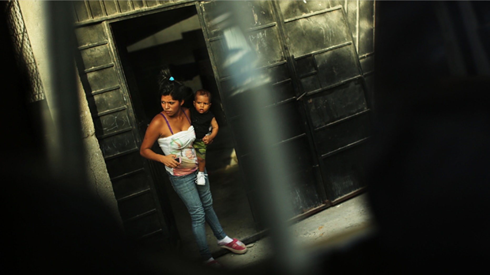 TEGUCIGALPA, HONDURAS - JULY 20: A woman and her son look out of a doorway in a neighborhood with heavy gang violence on July 20, 2012 in Tegucigalpa, Honduras. Honduras now has the highest per capita murder rate in the world and its capital city, Tegucigalpa, is plagued by violence, poverty, homelessness and sexual assaults. With an estimated 80% of the cocaine entering the United States now being trans-shipped through Honduras, the violence on the streets is a spillover from the ramped rise in narco-trafficking. (Photo by Spencer Platt/Getty Images)