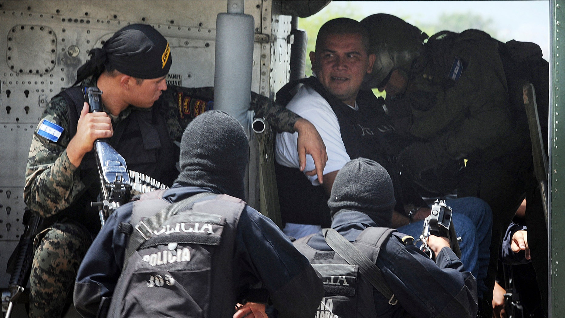 In this Monday, Oct. 10, 2011 photo, alleged drug trafficker Mario Ponce Rodriguez from Guatemala is escorted by police and army personnel during his extradition to the U.S. from Tegucigalpa, Honduras. Honduras has become a main transit route for South American cocaine, a trend that has helped drive the country's homicide rate to the highest level in the world and left many villages dependent on the cocaine trade. (AP Photo/Fernando Antonio)