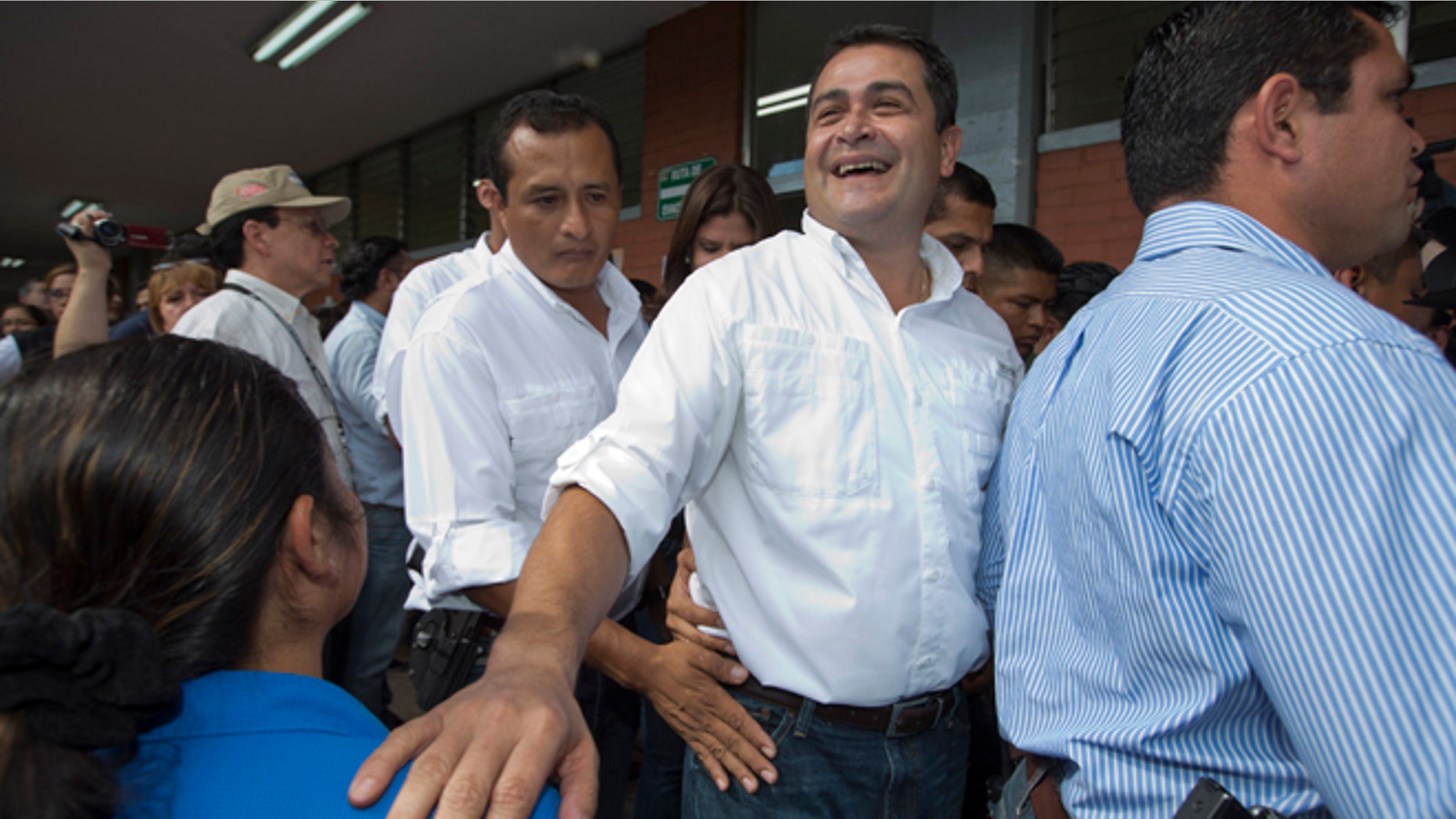 FILE - In this Nov. 24, 2013, file photo, then National Party Presidential Candidate Juan Orlando Hernandez, second from right, greets supporters at a polling station in Tegucigalpa, Honduras. Now as President of Honduras, Hernandez has acknowledged Wednesday, June 3, 2015, that his election campaign received financing from businesspeople linked to a social security embezzlement and graft scandal that has sparked large protests, but denied any personal involvement. (AP Photo/Moises Castillo, File)