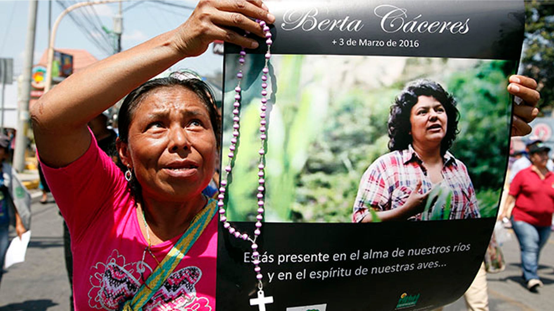 FILE - In this March 16, 2016, file photo, a woman holds up a poster with a photo of slain environmental leader Berta Caceres, during a protest march in Tegucigalpa, Honduras. Authorities said that unidentified gunmen killed Nelson Garcia, a colleague of Caceres, who was slain almost two weeks ago in similar circumstances. Honduran authorities announced Thursday, Sept. 8, that they have arrested a sixth suspect in the March killing of environmental activist Berta Caceres. (AP Photo/Fernando Antonio, File)