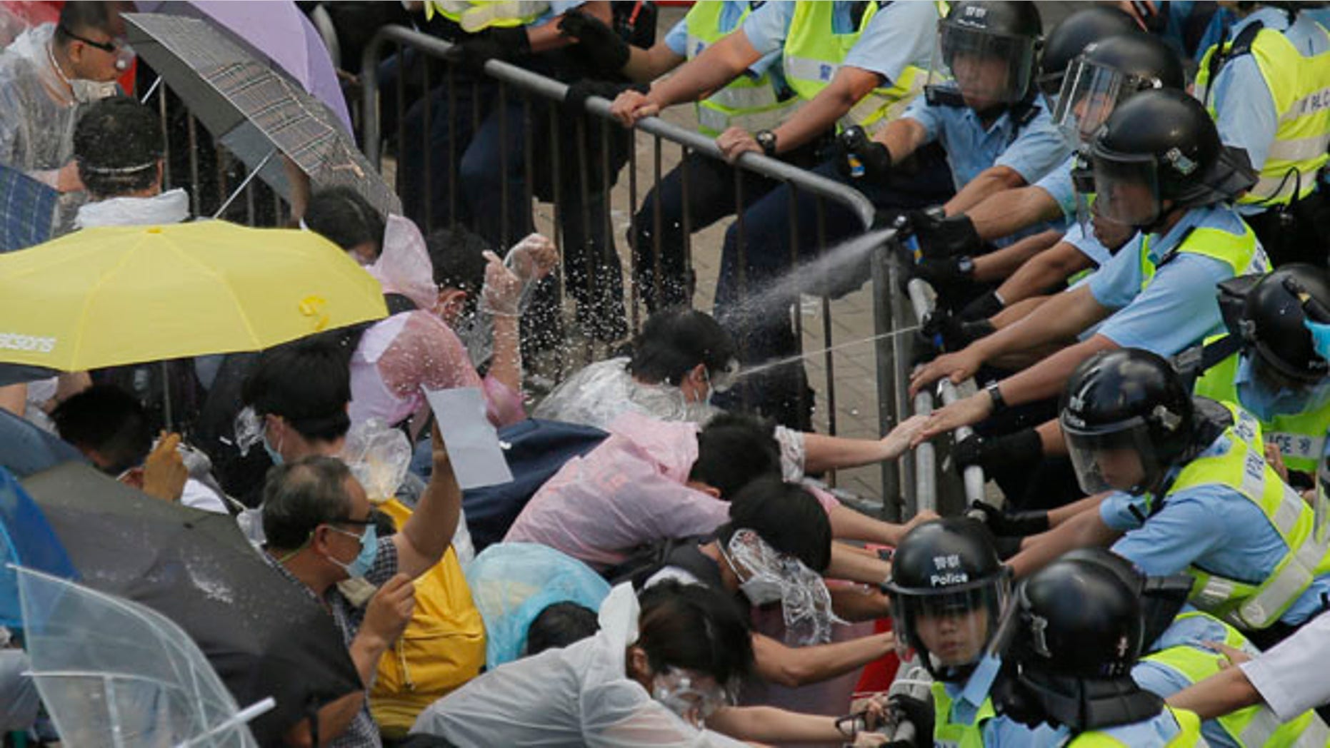 September 28, 2014: Riot police use pepper spray against protesters after thousands of people block a main road to the financial central district outside the government headquarters in Hong Kong. (AP Photo/Vincent Yu)