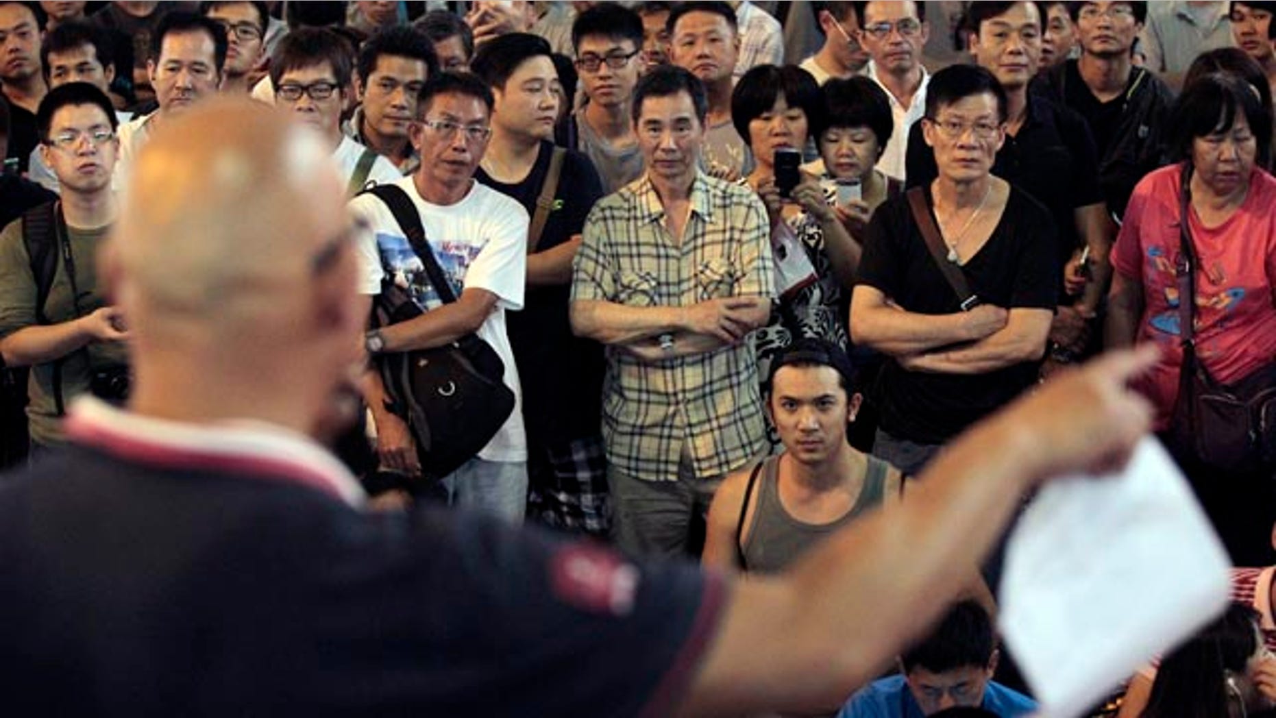 October 20, 2014: Passers by stop and listen to speeches by protest leaders at the pro-democracy protest site in the Mong Kok district of Hong Kong. (AP Photo/Wally Santana)