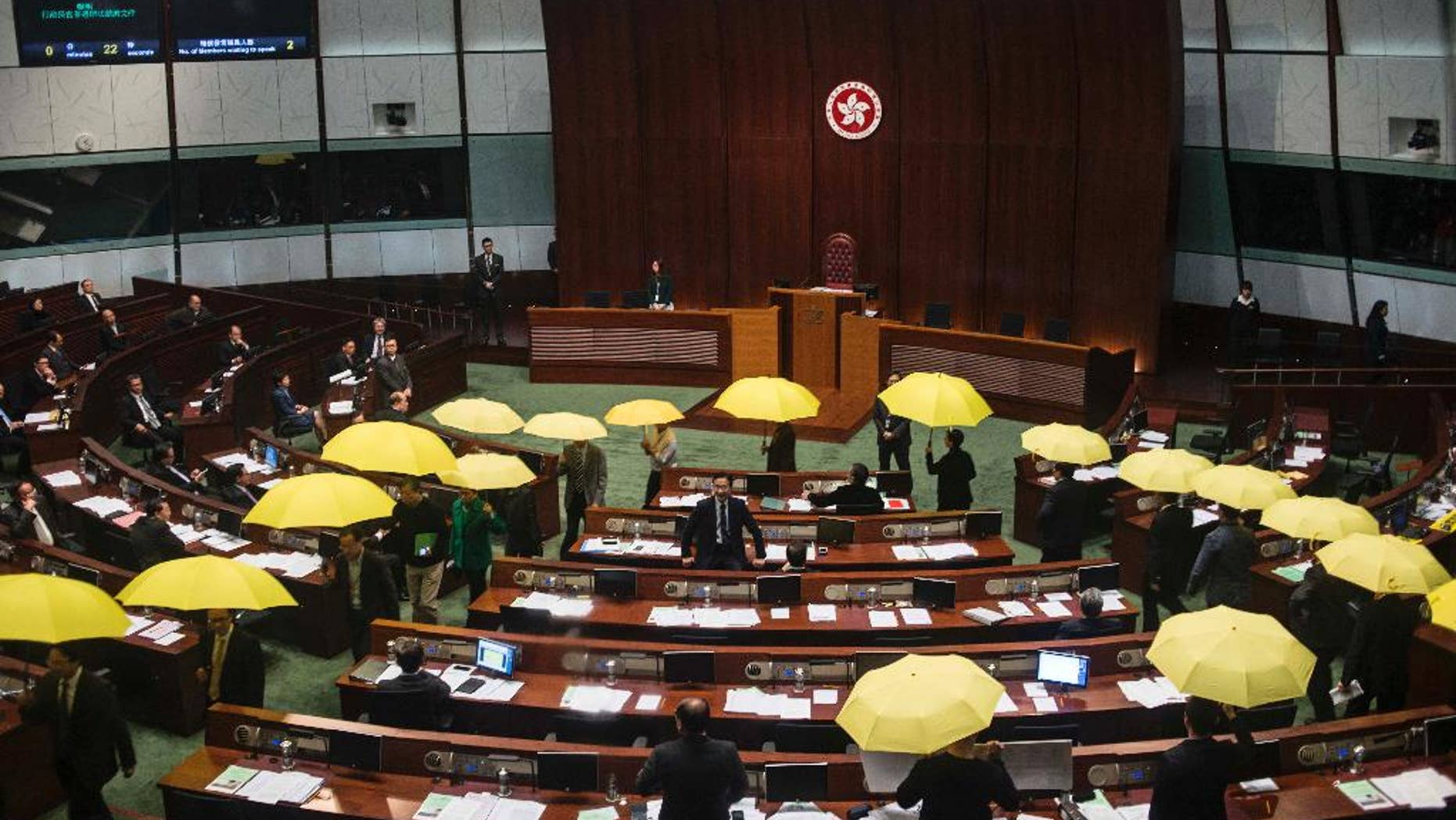 Pro-democracy legislators holding yellow umbrellas walk out of the Legislative chamber to show their protest in Hong Kong, Wednesday, Jan. 7, 2014. Pro-democracy legislators walked out of the chamber Wednesday to protest the government's intention to stick with a proposal to screen candidates for the city's top executive in 2017, an issue that sparked massive street protests throughout the fall. (AP Photo)