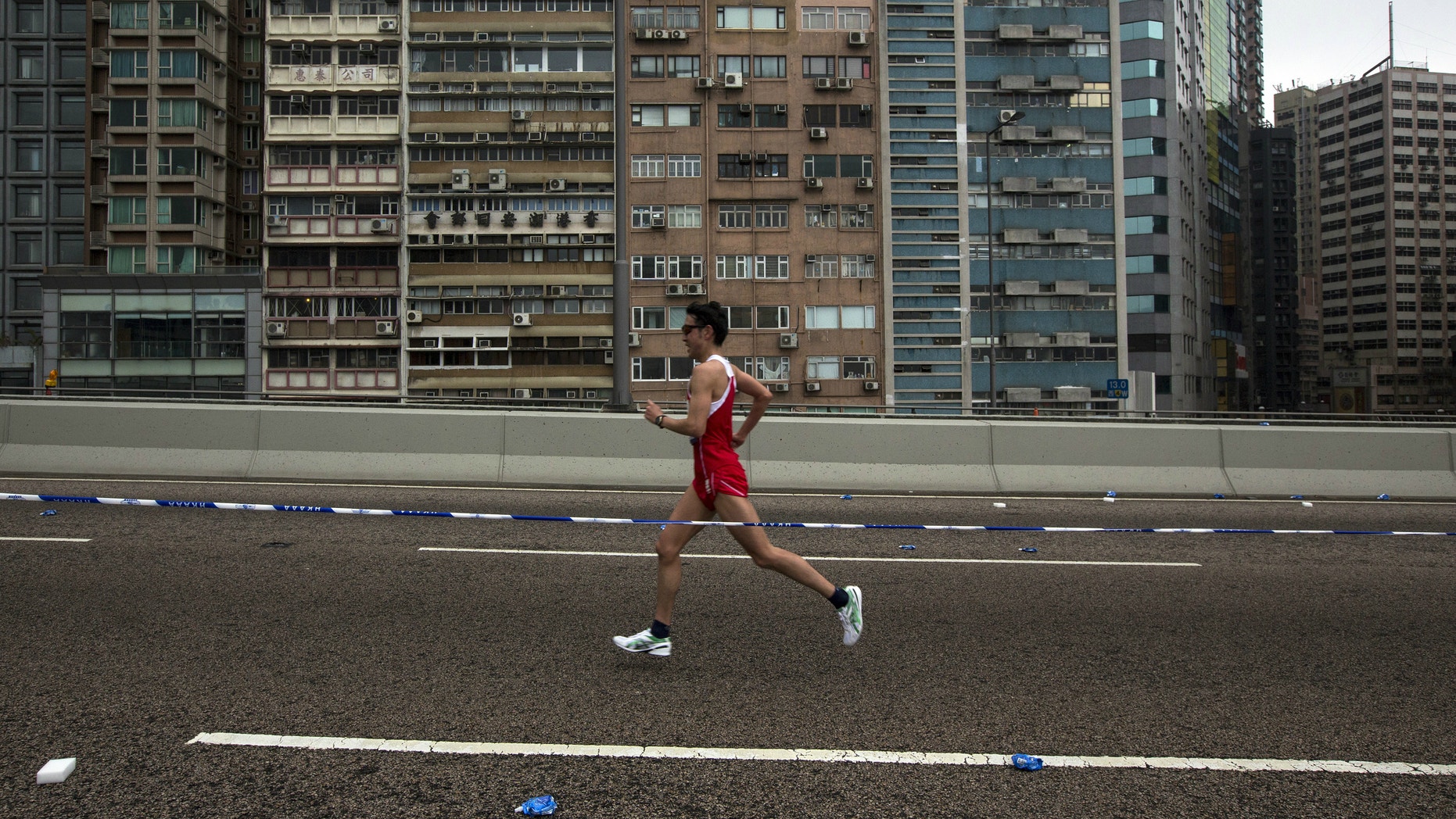 A participant runs past a old residential zone on the Connaught Road West Flyover as he competes in the Hong Kong marathon.