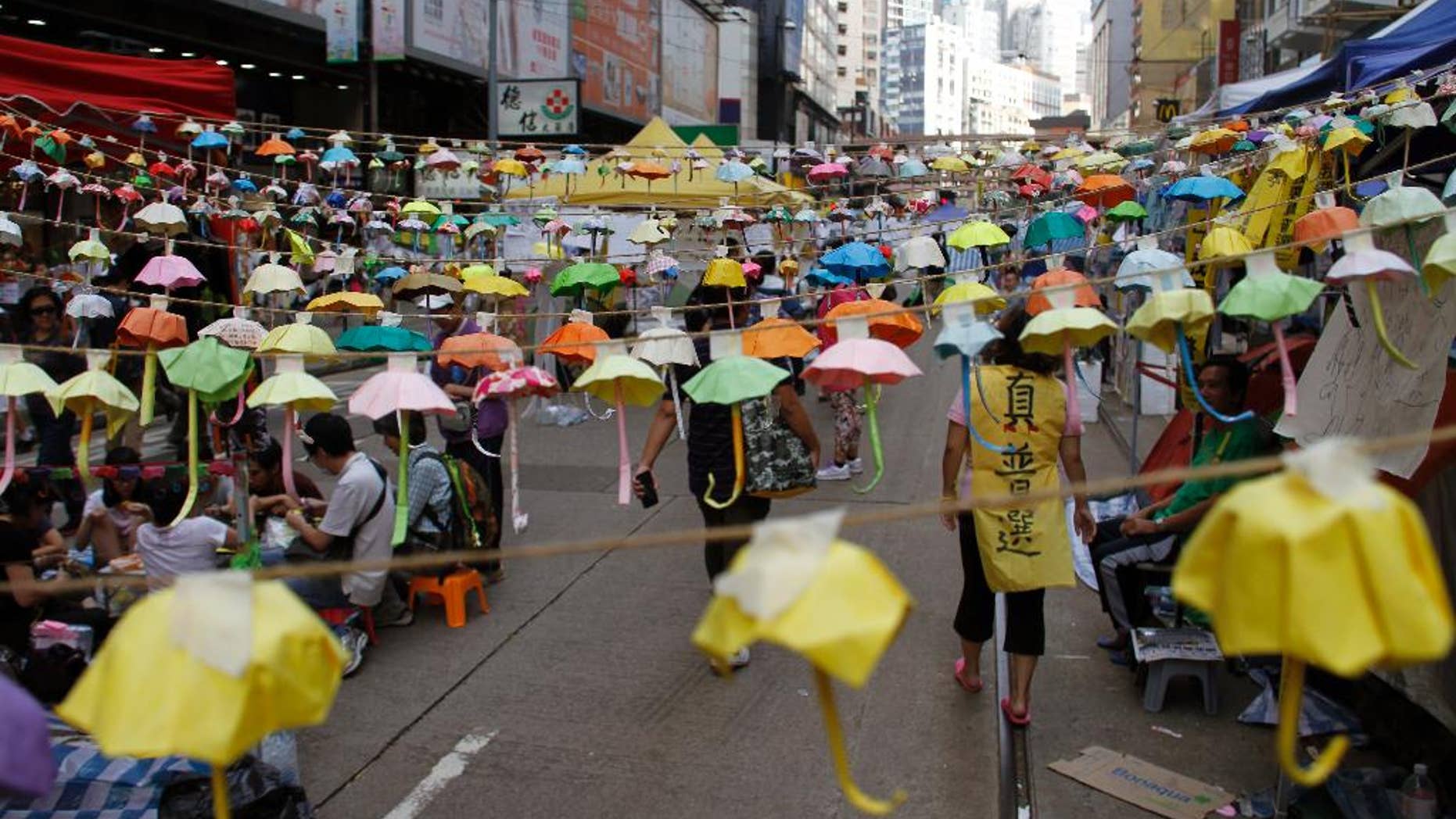 Protesters and people walk under hundreds of folded paper umbrellas at the occupied area in Causeway Bay, a shopping district of Hong Kong Thursday Oct. 30, 2014. Student democracy activists who have occupied Hong Kong streets for a month suggested Tuesday that direct negotiations with senior Chinese Communist Party officials could be a way to end their standoff with the local government. (AP Photo/Koji Ueda)