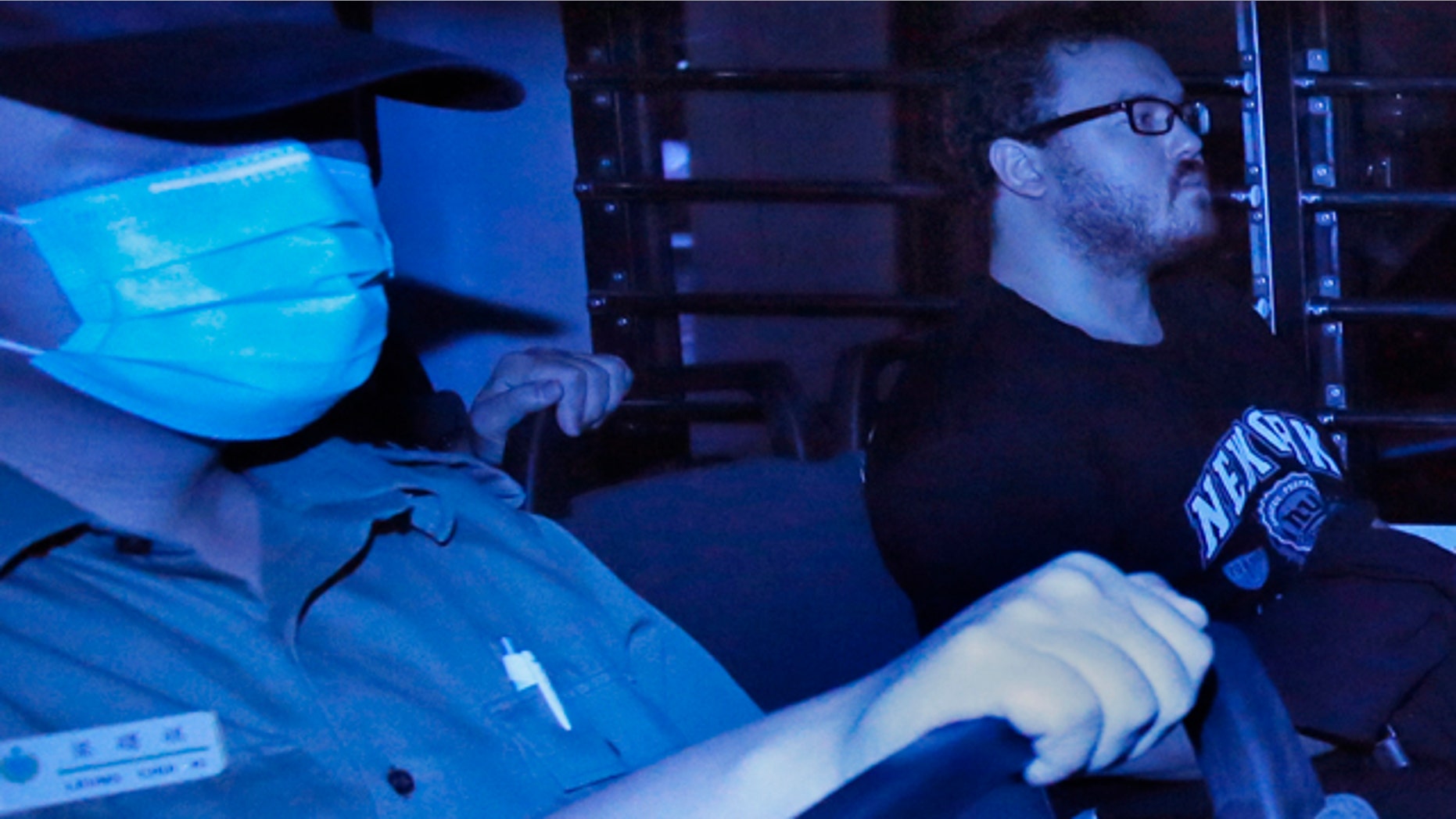 November 10, 2914: In this photo taken through tinted glass, Rurik George Caton Jutting, right, a 29-year-old British banker, is escorted by Correctional Services officers in a prison bus arriving at a court in Hong Kong. (AP Photo/Vincent Yu)
