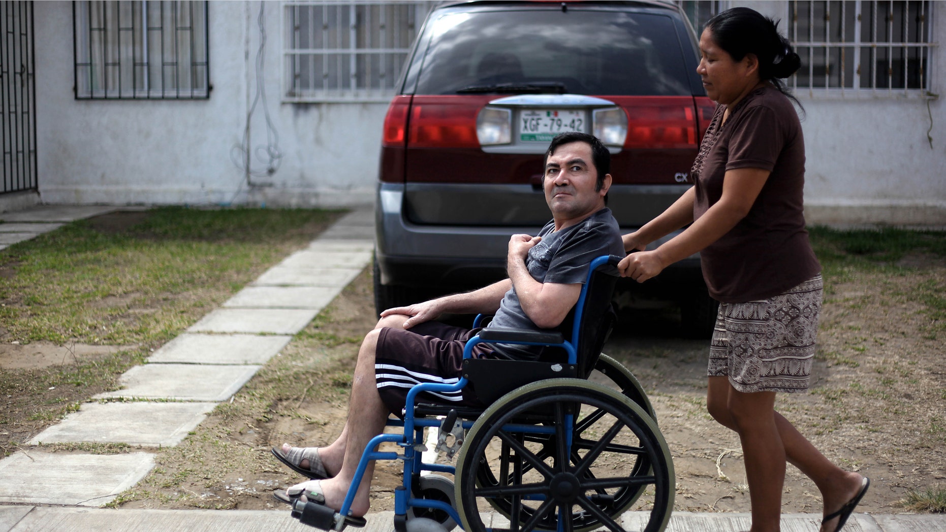 In this Thursday March 7, 2013 photo, Jacinto Rodriguez Cruz, 49, leaves his home on a wheelchair with the help of his wife, Belen Hernandez in the city of Veracruz, Mexico. Cruz and another friend suffered serious injuries during a car accident last May 2008 in northwestern Iowa. After their employers insurance coverage ran out, Cruz, who was not a legal citizen, was placed on a private airplane and flown to Mexico still comatose and unable to discuss his care or voice his protest. Hospitals confronted with absorbing the cost of caring for uninsured seriously injured immigrants are quietly deporting them, often unconscious and unable to protest, back to their home countries. (AP Photo/Felix Marquez)