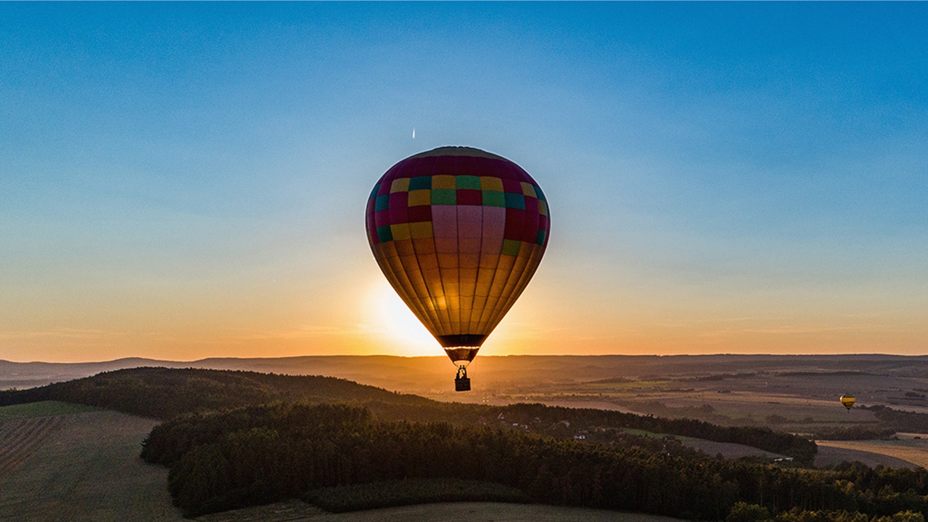 Hot air balloon in flight in the backlight of the setting sun.