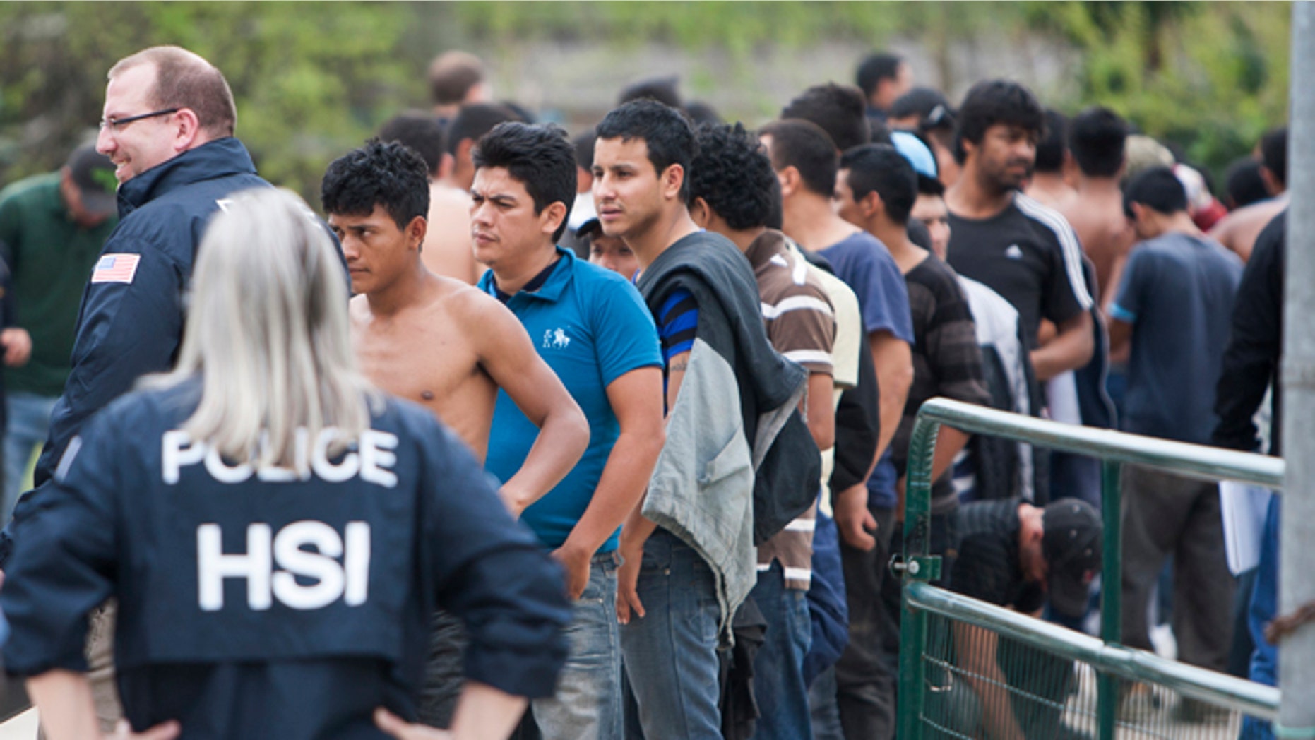 People wait outside a house as authorities hold an investigation, Wednesday, March 19, 2014, in southeast Houston. A house overflowing with more than 100 people presumed to be in the United States illegally was uncovered just outside Houston on Wednesday, a police spokesman said. The suspected stash house was found during a search for a 24-year-old woman and her two children that were reported missing by relatives Tuesday after a man failed to meet them, said a spokesman for the Houston Police Department. (AP Photo/Houston Chronicle, Cody Duty)