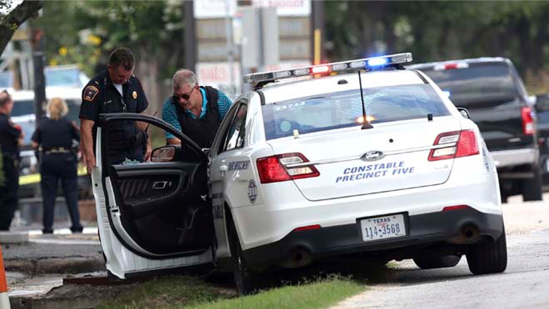 A C=constable car with a shot-out window remains at the scene where Houston police were investigating a shooting, Sunday, May 29, 2016, in Houston. A man came into an auto detail shop and began shooting, killing a man known to be a customer and putting a neighborhood on lockdown before being killed by a SWAT officer, police said. Several people were shot and injured. (Elizabeth Conley/Houston Chronicle via AP)