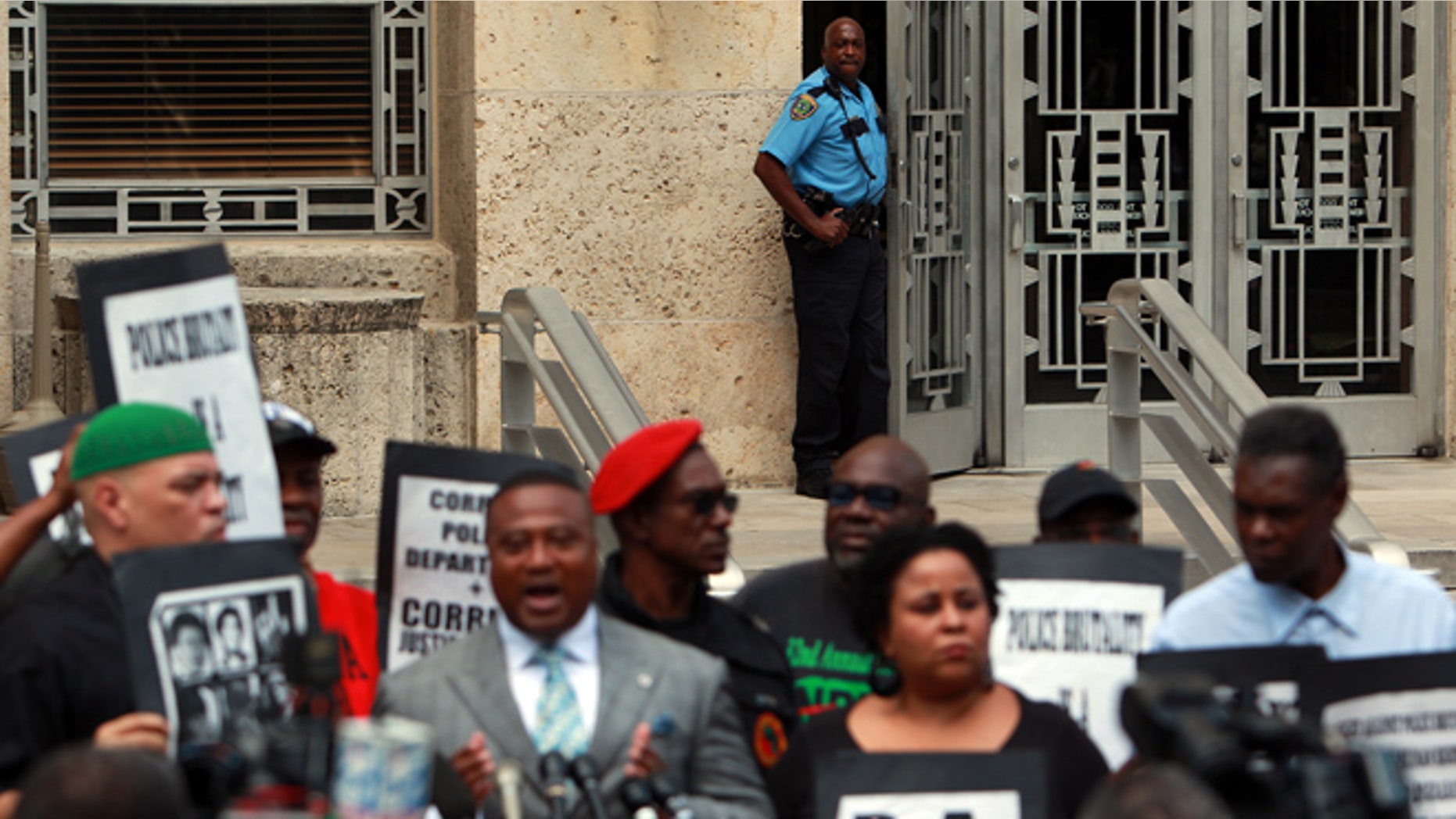 Sept. 25, 2012: An HPD officer peeks out of a door at City Hall as activists call for answers from city officials on why a police officer on Saturday fatally shot Brian Claunch outside City Hall in Houston.