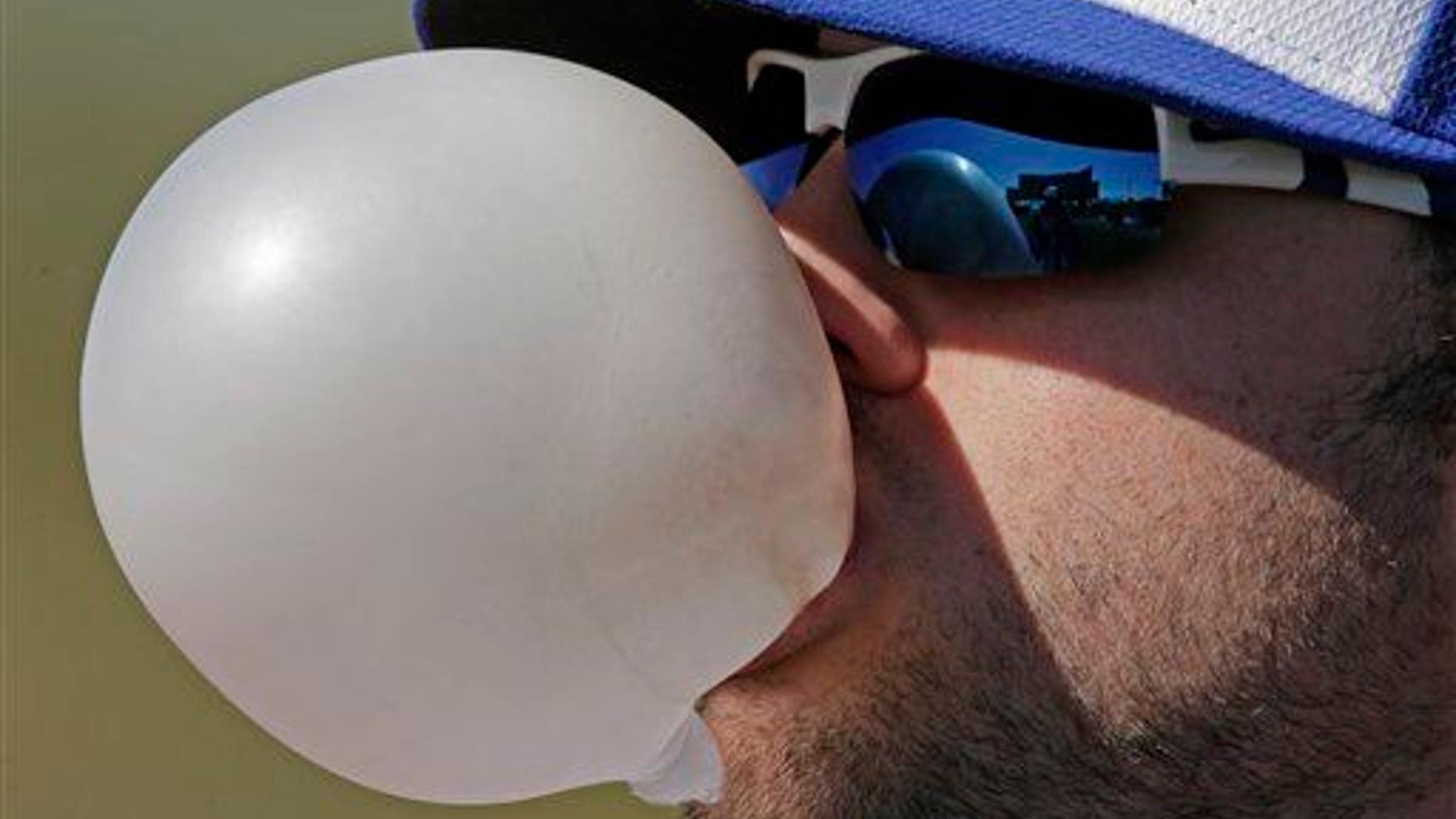 Kansas City Royals third baseman Mike Moustakas blows a chewing gum bubble, removes bacteria from his oral cavity.