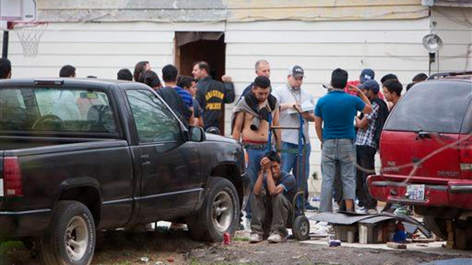 People wait outside a house, Wednesday, March 19, 2014, in southeast Houston.