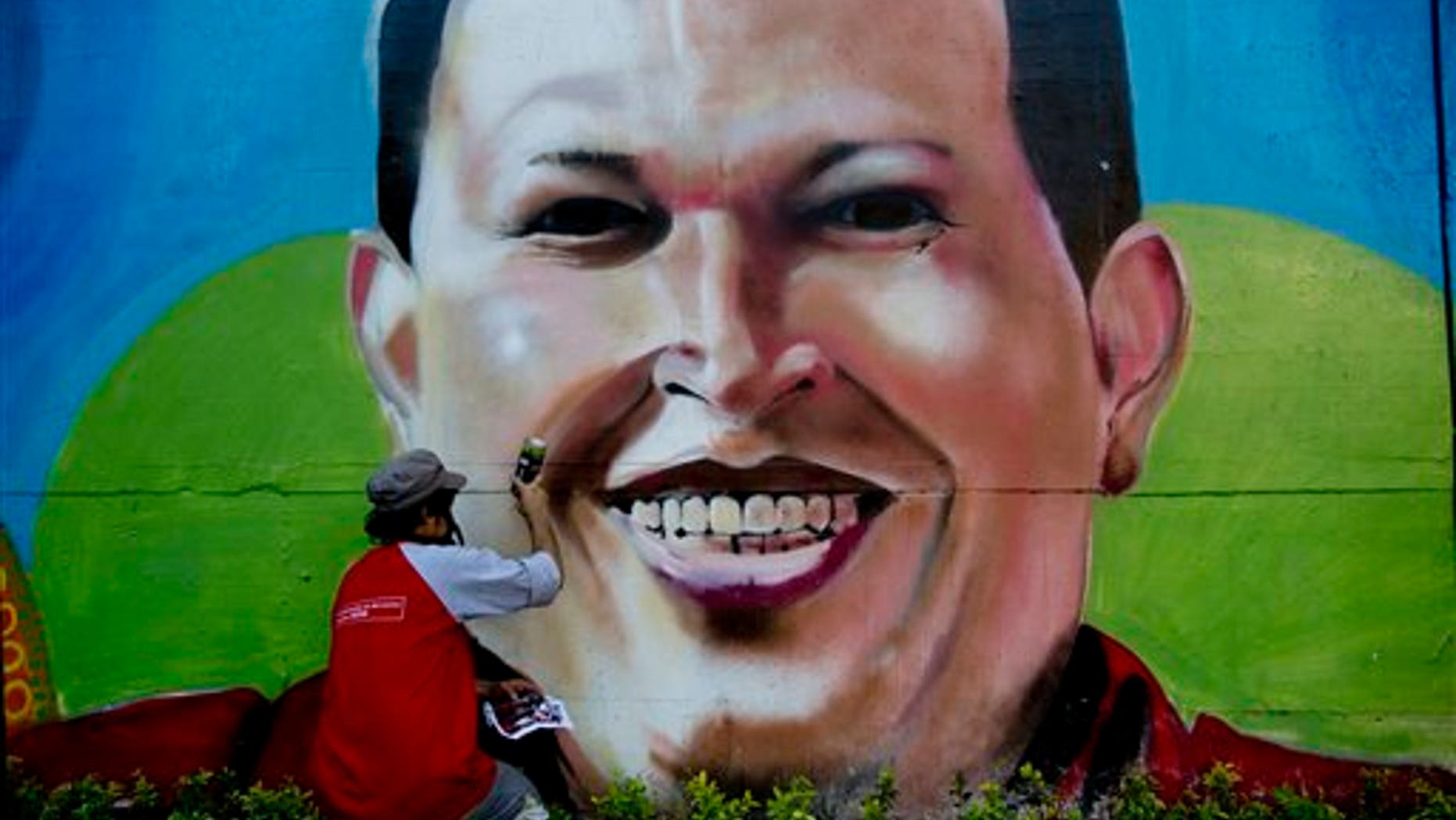 FILE.- In this Tuesday, Feb. 25, 2014 file photo, artist Nicolay Shamanika retouches a mural of Venezuela's former President Hugo Chavez in Caracas, Venezuela. Heartfelt devotion is a crucial but fading force for Chavezs hand-picked successor, President Nicolas Maduro. Despite daily invocations of his mentor, and control of the powerful party apparatus he inherited, Maduro is increasingly on his own in a fight against a destabilizing wave of anti-government protests.(AP Photo/Rodrigo Abd, File)