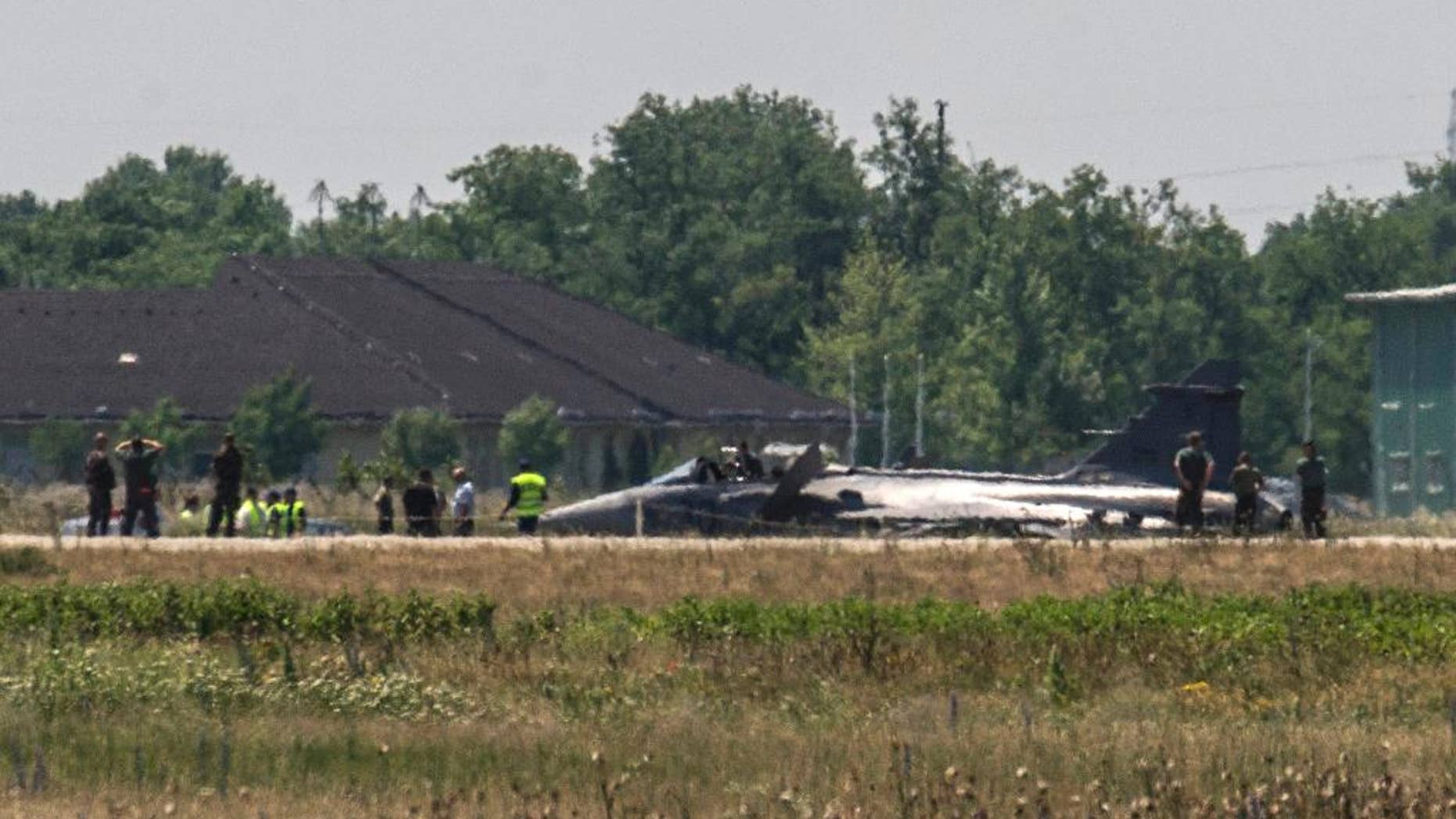 Military experts examine a JAS-39 C Gripen fighter jet of the Hungarian Defence Forces resting on the tarmac of the air base of Kecskemet, 85 kms southeast of Budapest, Hungary, after an emergency landing forced by a technical failure having occurred after take-off Wednesday, June 10, 2015. The pilot catapulted successfully, he is currently kept under medical control. (Sandor Ujvari/MTI via AP)