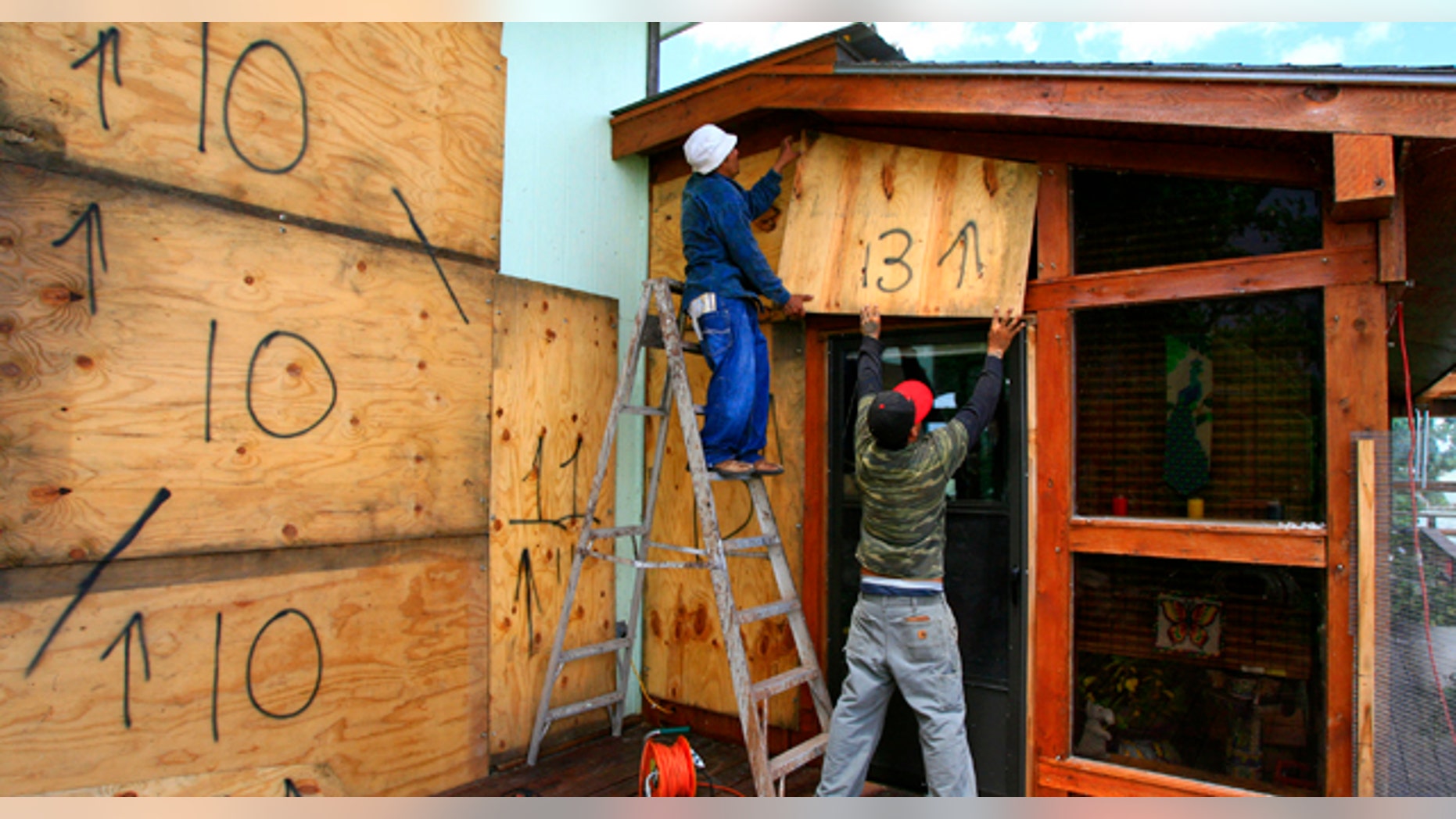 June 29: Norecio Salazar and Leonardo Salinas place a sheet of designated plywood over a window on Jim and JoAnne Farber's home on the Delta Lake Reservoir in preparation for Tropical Storm Alex. (AP)