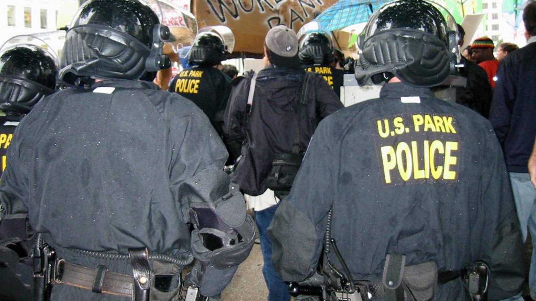 FILE - In this Sept. 26, 2002 file photo, police monitor a small demonstration outside the World Bank building in Washington. A proposed $2.2 million settlement of a case that started with the arrests of hundreds of protesters in 2002 would change how U.S. Park Police handle mass arrests. U.S. District Judge Emmet Sullivan issued preliminary approval for the settlement of the 12-year-old class action lawsuit last week. The lawsuit stems from about 400 arrests during International Monetary Fund and World Bank meetings in 2002. (AP Photo/Elizabeth Wolfe, File)