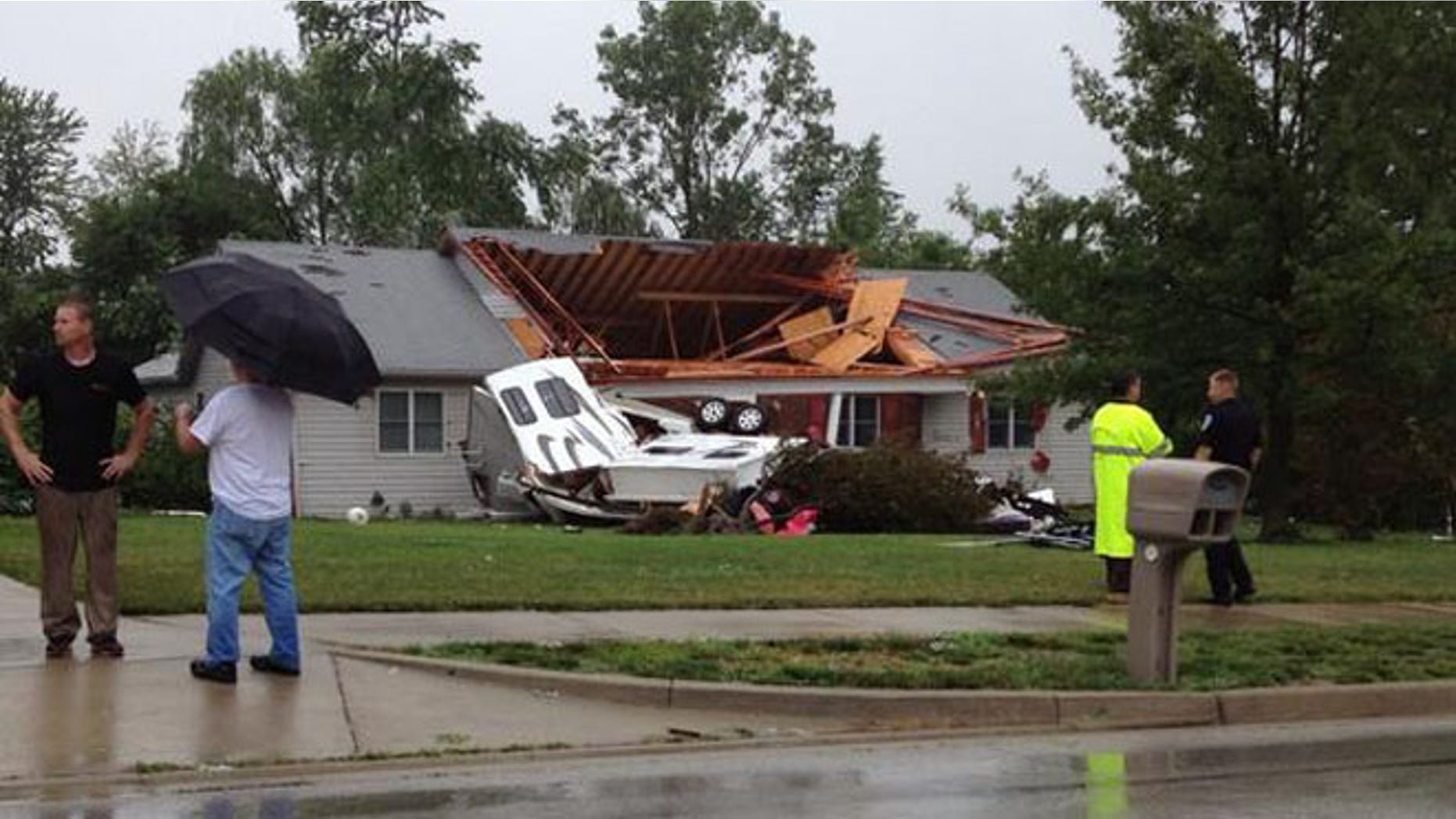 June 24, 2014: Residents stand outside a home that was badly damaged by a tornado in Plainfield, Indiana.
