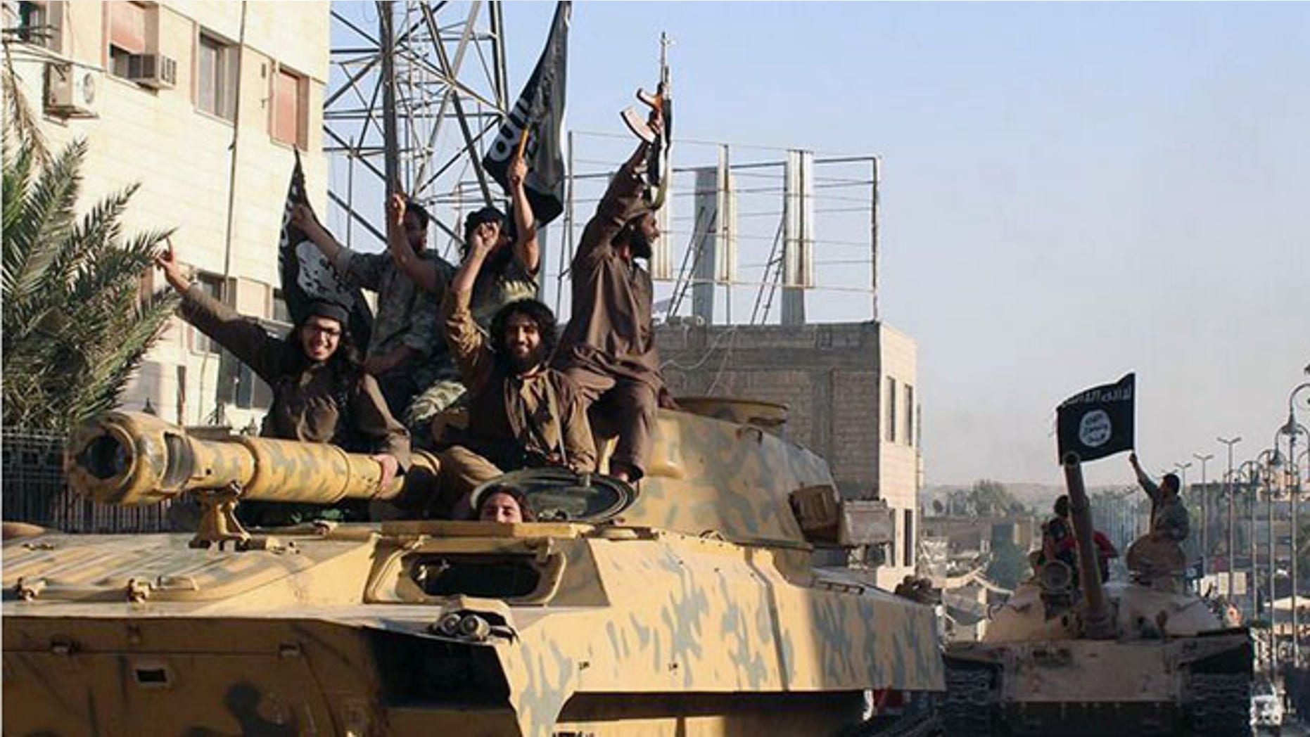 FILE - In this undated image posted by the Raqqa Media Center, in Islamic State group-held territory, on Monday, June 30, 2014, which has been verified and is consistent with other AP reporting, fighters from the al-Qaida linked Islamic State of Iraq and the Levant (ISIL) ride tanks during a parade in Raqqa, Syria. (Raqqa Media Center via AP, File)