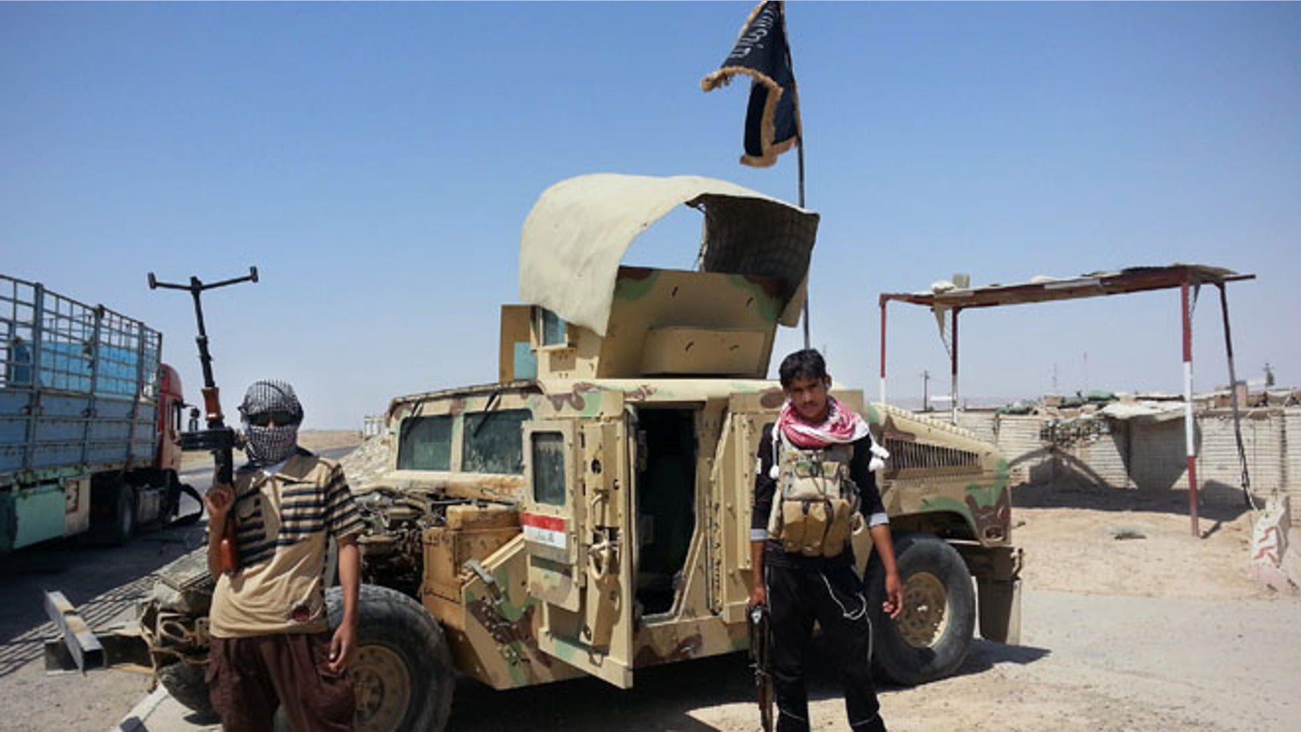 In this file photo taken Thursday, June 19, 2014, ISIS militants stand with captured Iraqi Army Humvee.