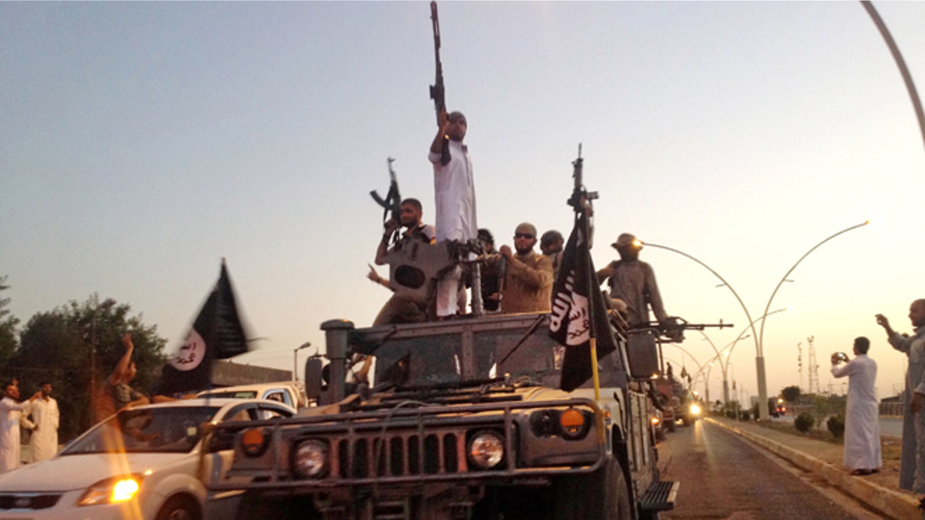 In this file photo taken Monday, June 23, 2014, fighters from the Islamic State group parade in a commandeered Iraqi security forces armored vehicle down a main road at the northern city of Mosul, Iraq.