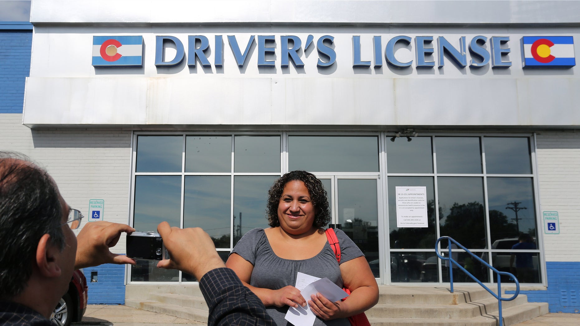 FILE - In this Aug. 1, 2014 file photo, immigrant and longtime resident in the United States Rosalva Mireles is photographed by Jesus Sanchez of Spanish language newspaper El Commercio, after Mireles was processed for her permanent driver's license, and received a temporary one to use until it is ready, at a Department of Motor Vehicles office, in Denver. Colorado Democrats are decrying a Republican decision to not add funding to a program allowing immigrants to get driver's licenses regardless of their legal status. There's been high demand for the program since it launched last year. (AP Photo/Brennan Linsley, file)