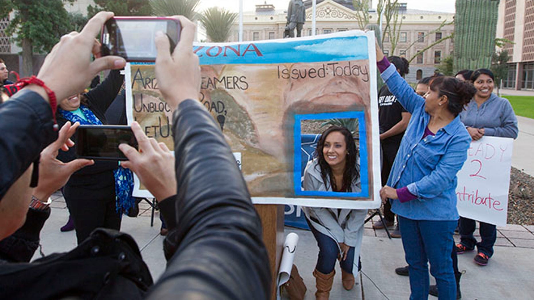 FILE - In this Dec 17, 2014, file photo, Erika Andiola gets her photo taken at the Arizona State Capitol in Phoenix, as thousands of young immigrants moved a step closer to getting driver's licenses in Arizona. A single mother battling cancer and a victim of domestic abuse are among the immigrants who qualify for Arizona driver's licenses but have been illegally denied the chance to drive a car, a group of advocacy organizations said in a new federal lawsuit. Denying licenses to some immigrants in the country illegally who have been granted deferred action, or protection from deportation, is unconstitutional, according to the claim filed Monday, Sept. 12, 2016 by the Mexican American Legal Defense and Educational Fund, the National Immigration Law Center and the Ortega Law Firm.(Nick Oza /The Arizona Republic via AP, File)