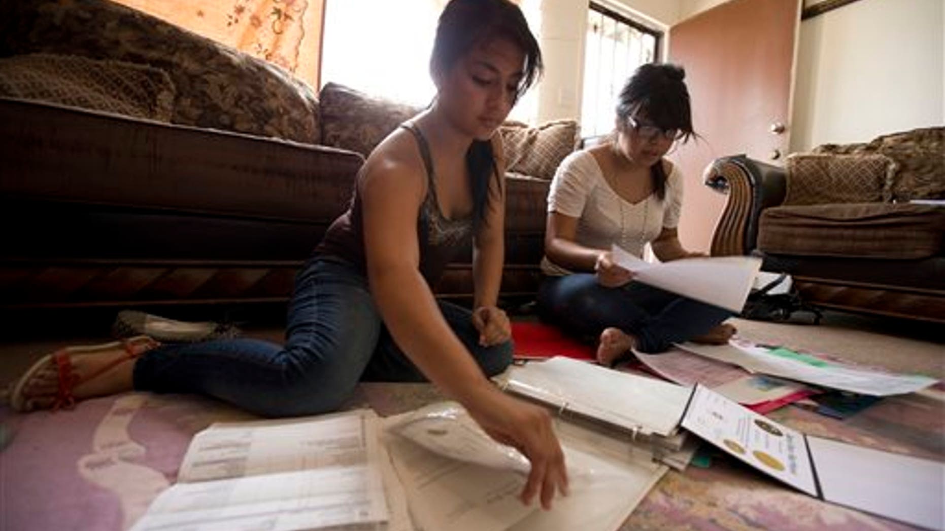 Itzel Guillen, left, sorts out some of the documents she needs to apply for a work permit along with Lucero Maganda, right, at her home in San Diego, Ca. Guillen and Maganda are among those hoping for the right to work legally in America without being deported.(AP Photo/Gregory Bull, File)
